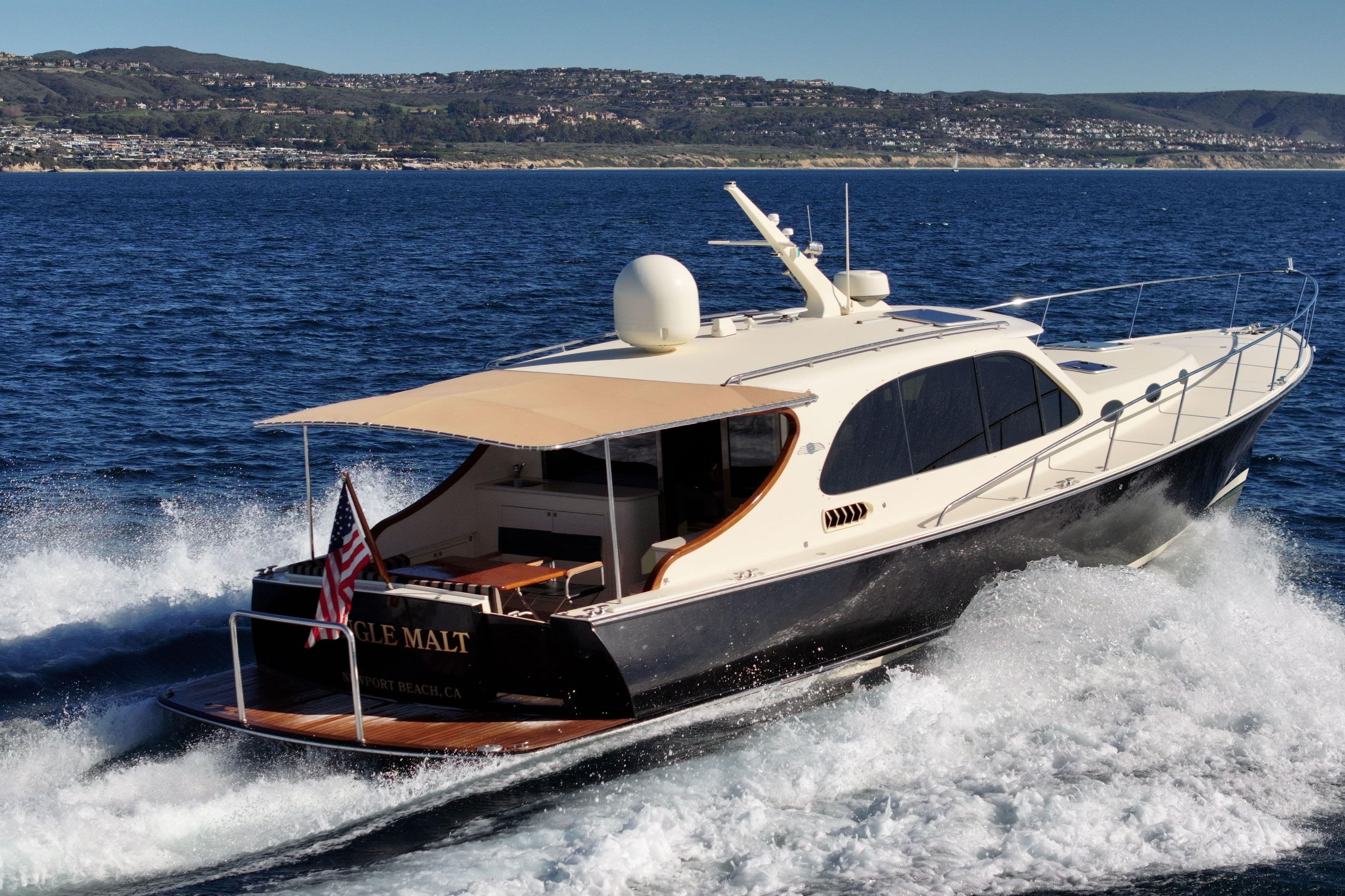 2015 Palm Beach Motor Yachts PB45 cruising on open water, scenic coastal backdrop.