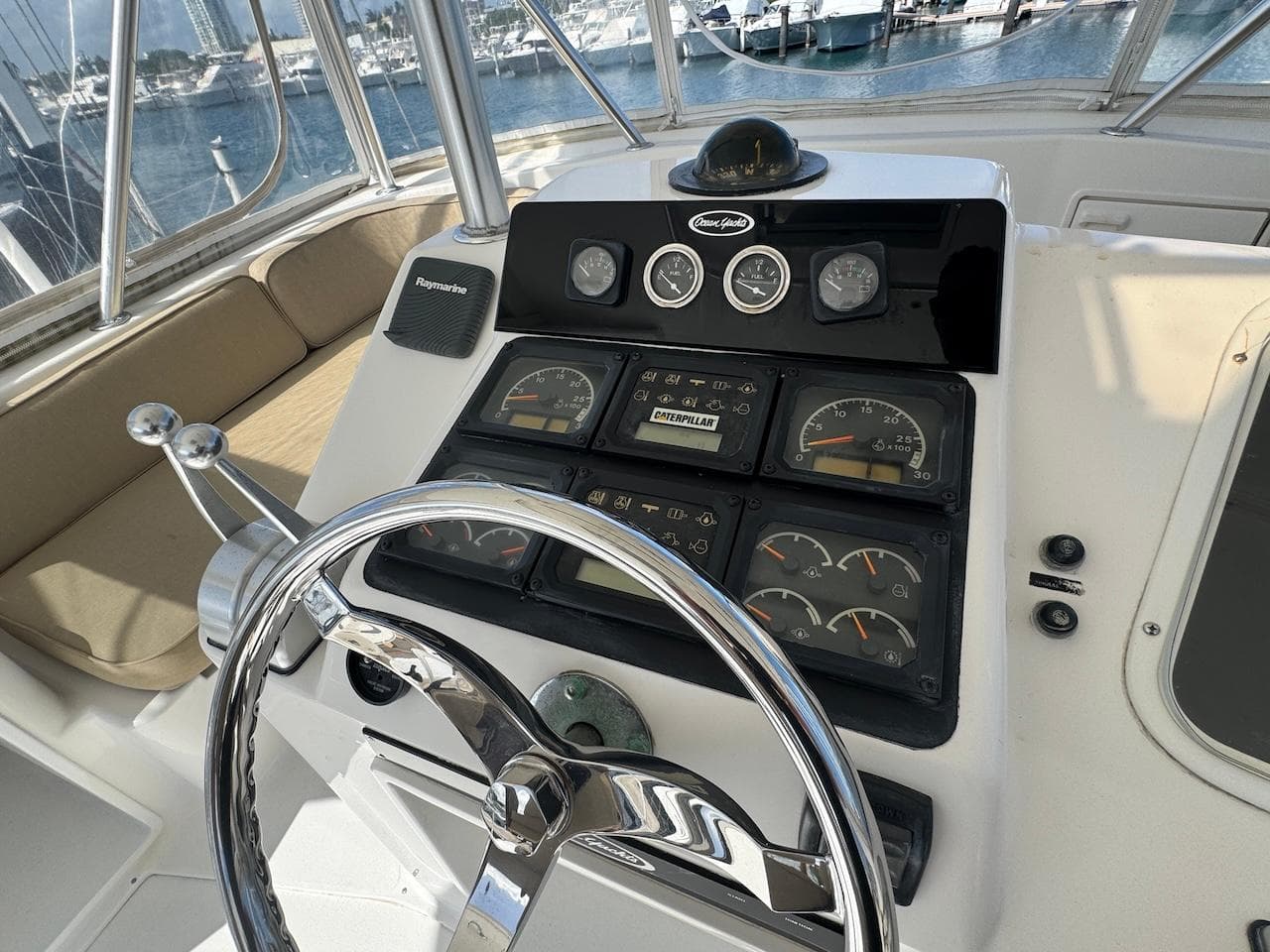 Helm of 2000 Ocean Yachts 48 Convertible with gauges and steering wheel, docked at marina.