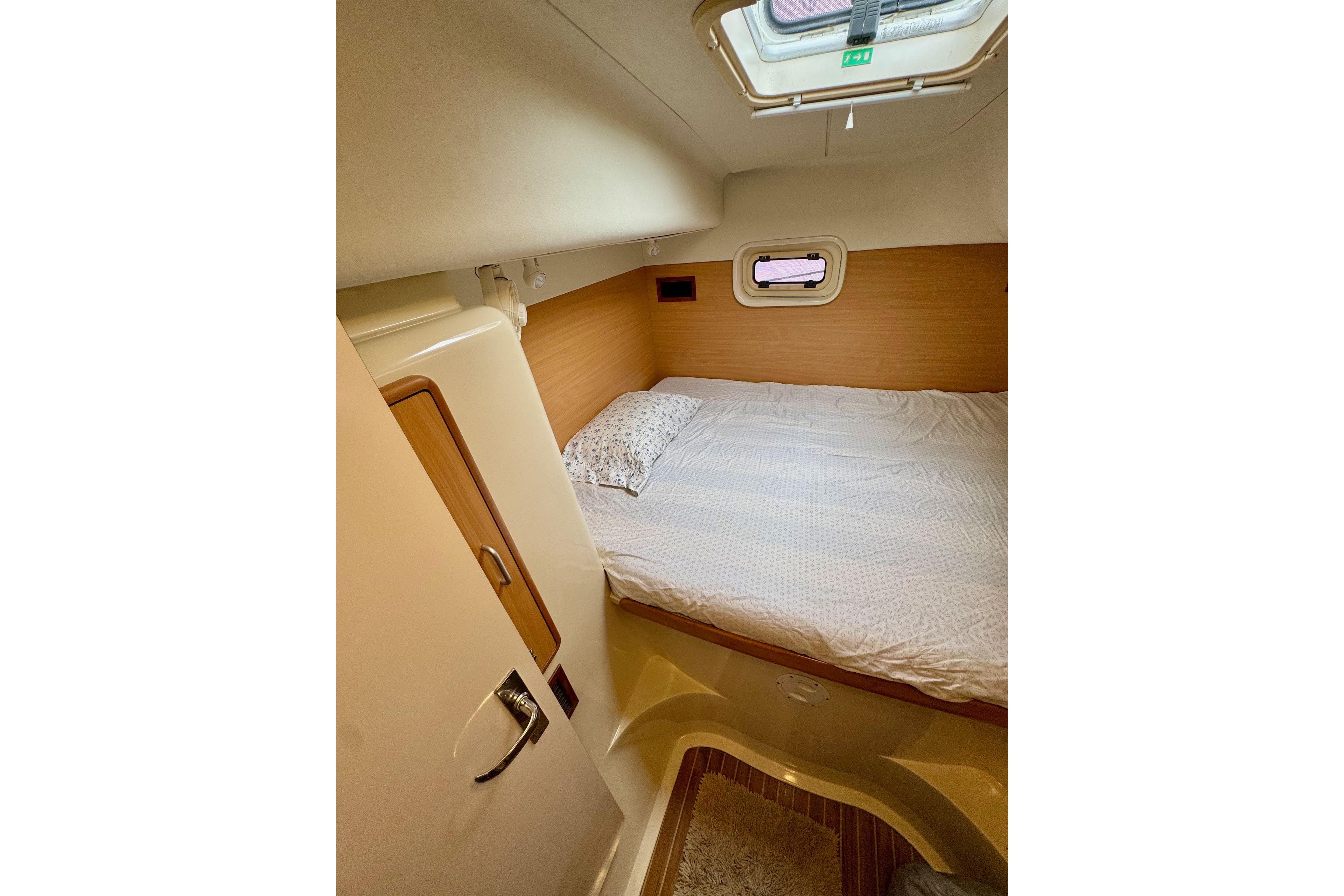 Cozy cabin interior of 2004 Leopard 42 yacht with bed and porthole.