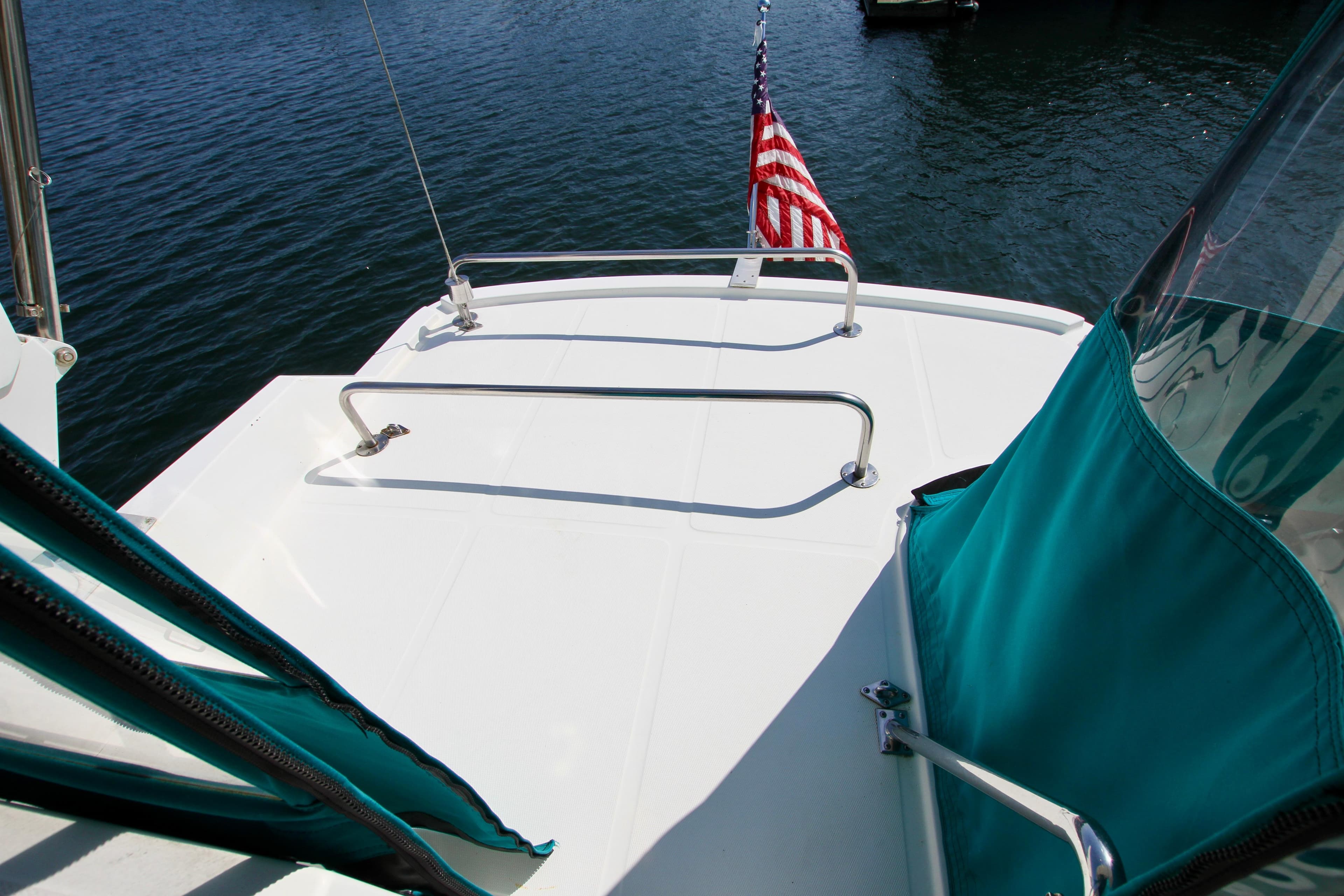 1999 McKinna 47 Sedan yacht deck with American flag, teal accents, and railing.