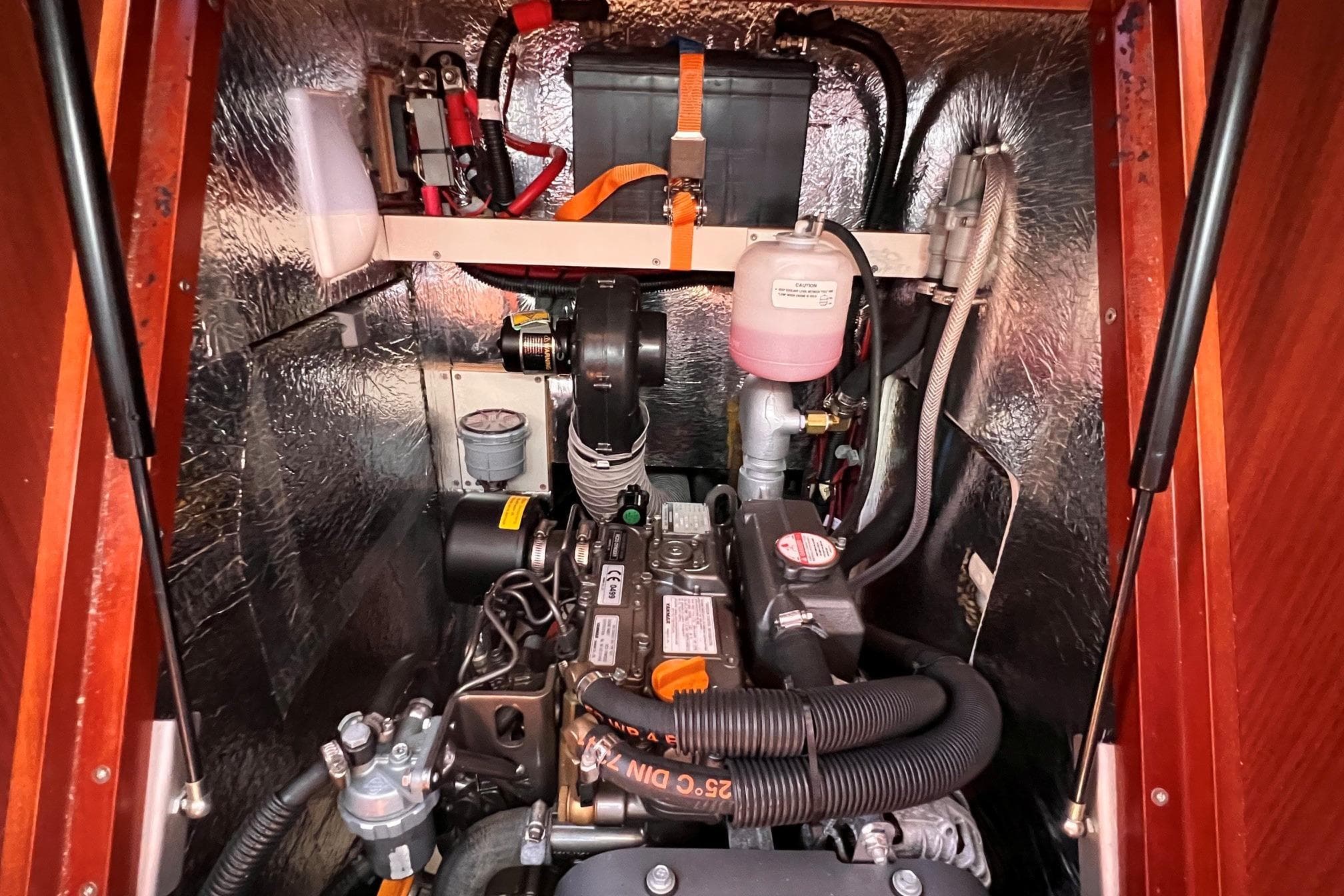 Engine compartment of a 2019 Dehler 34 sailboat, showcasing mechanical components and battery.