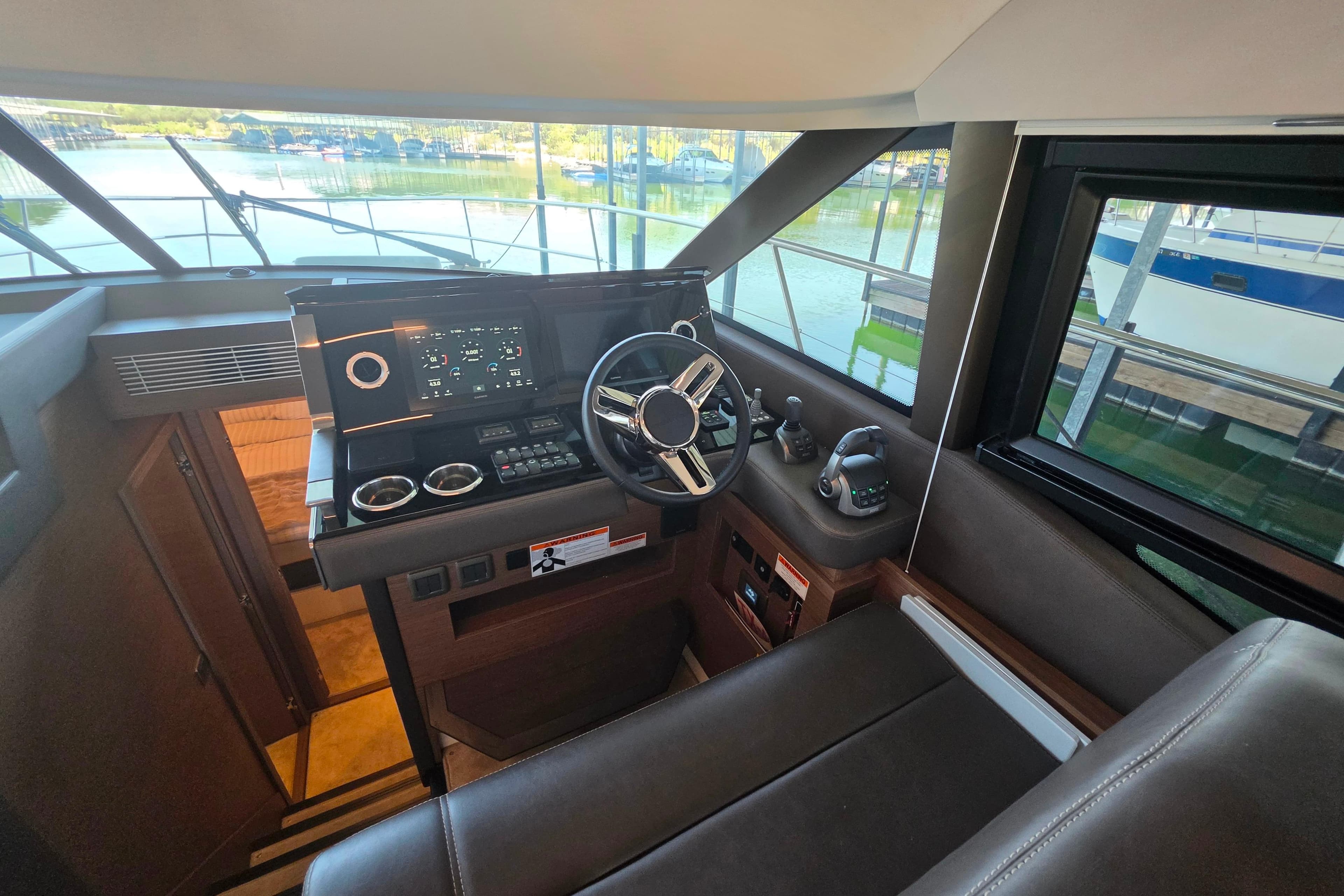 Helm of 2025 Prestige 460 yacht with modern controls and scenic marina view.