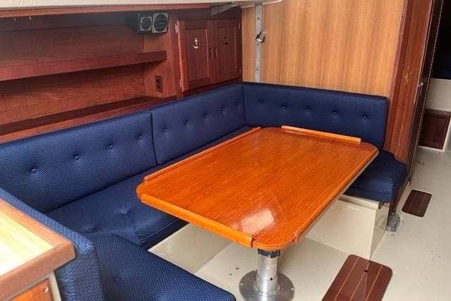 1982 Catalina 38 sailboat interior with blue cushioned seating and polished wooden table.