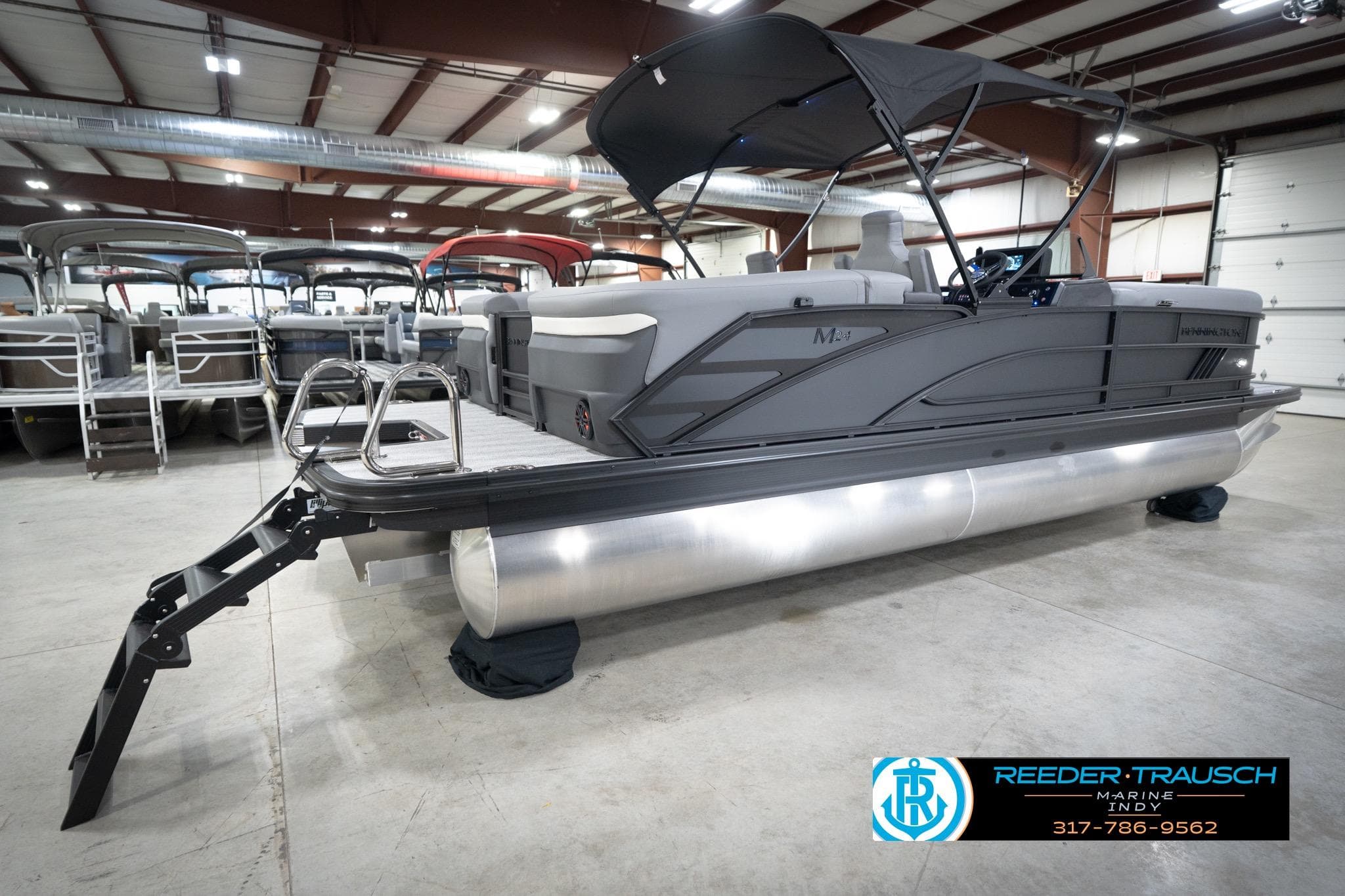 2026 Bennington 24 MFB pontoon boat in showroom with canopy and ladder.