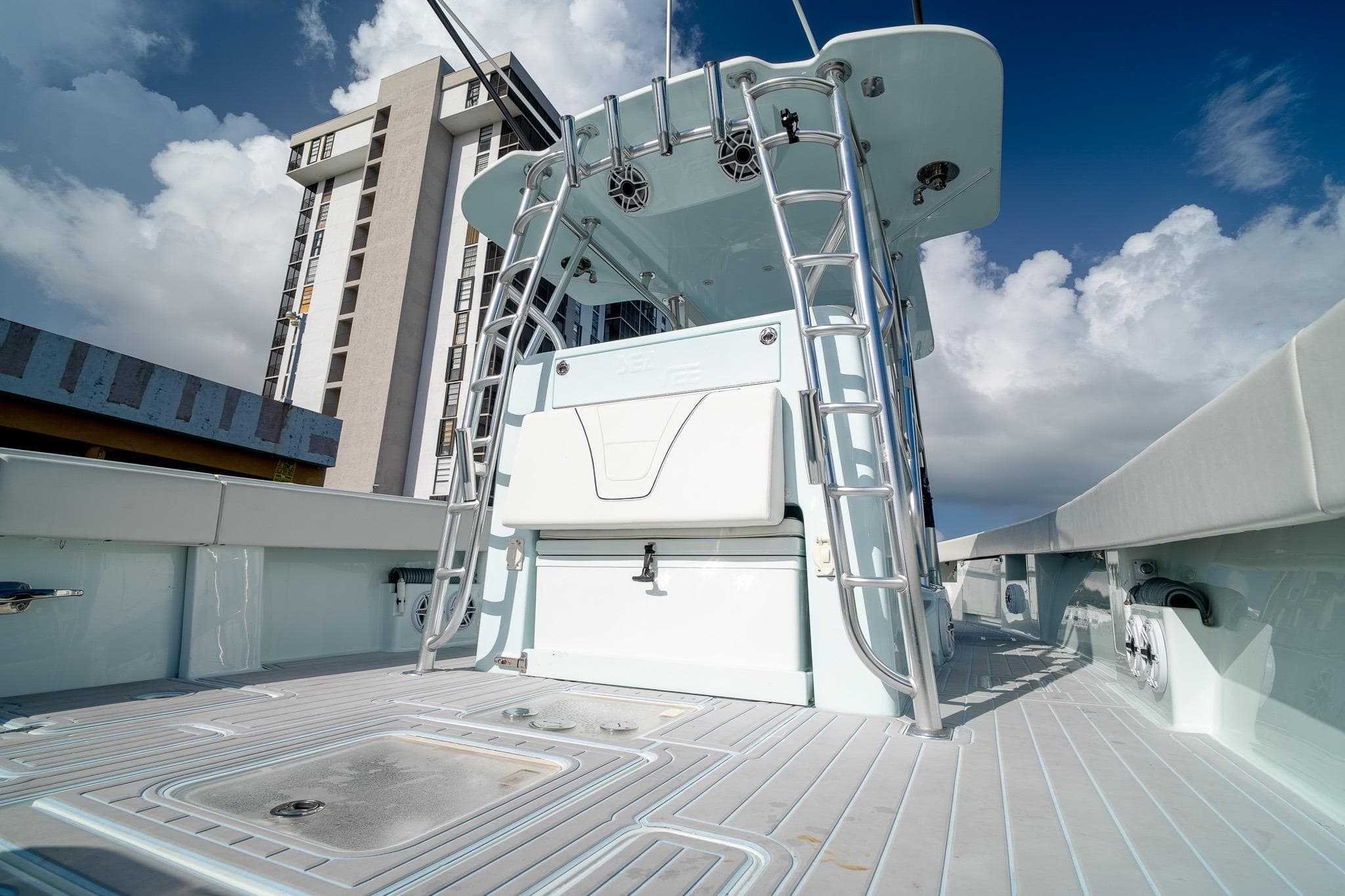 2023 SeaVee 390Z boat deck with ladder, against a cloudy sky and building backdrop.