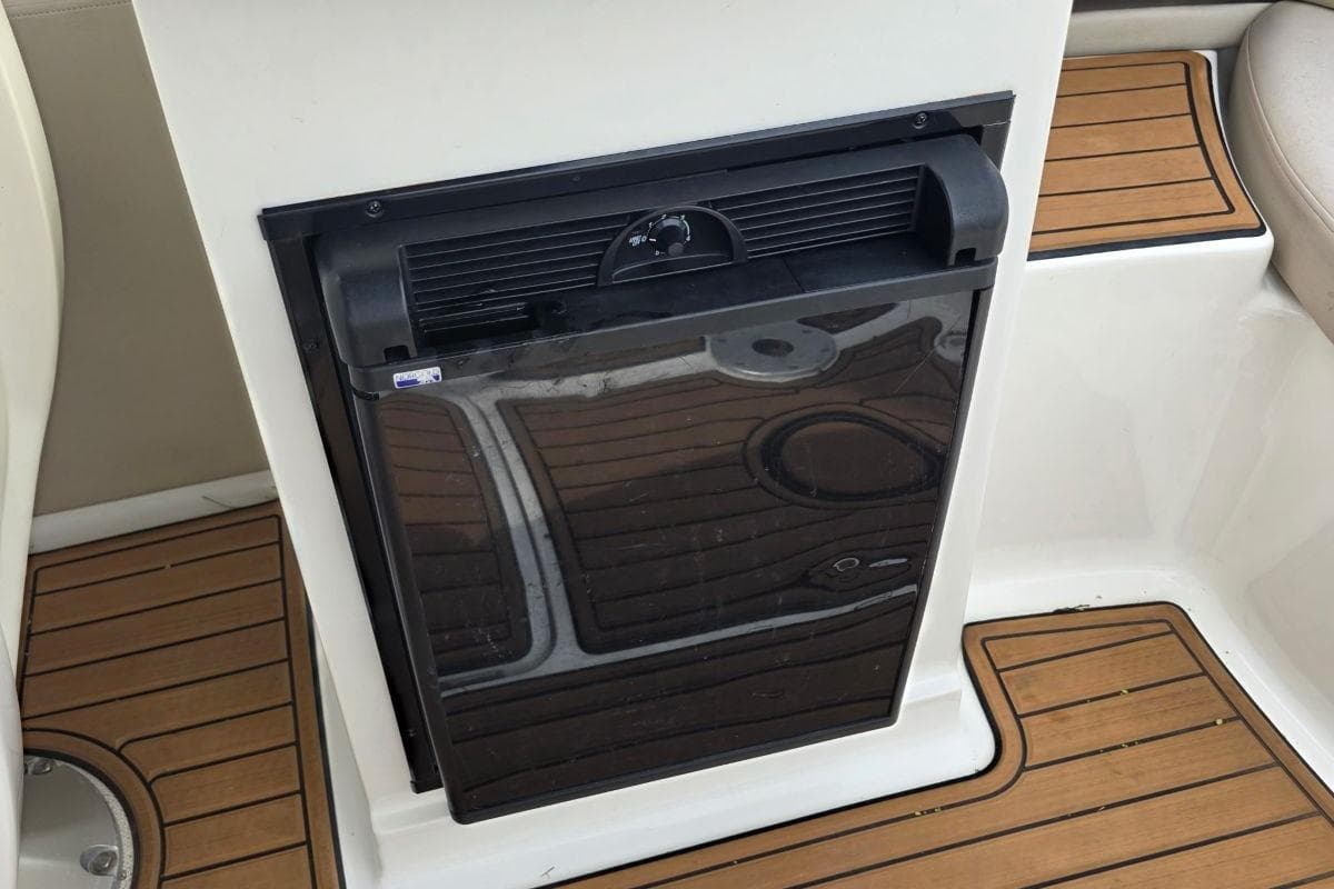 Built-in refrigerator on 2011 Sea Ray SLX 250 boat with teak flooring.