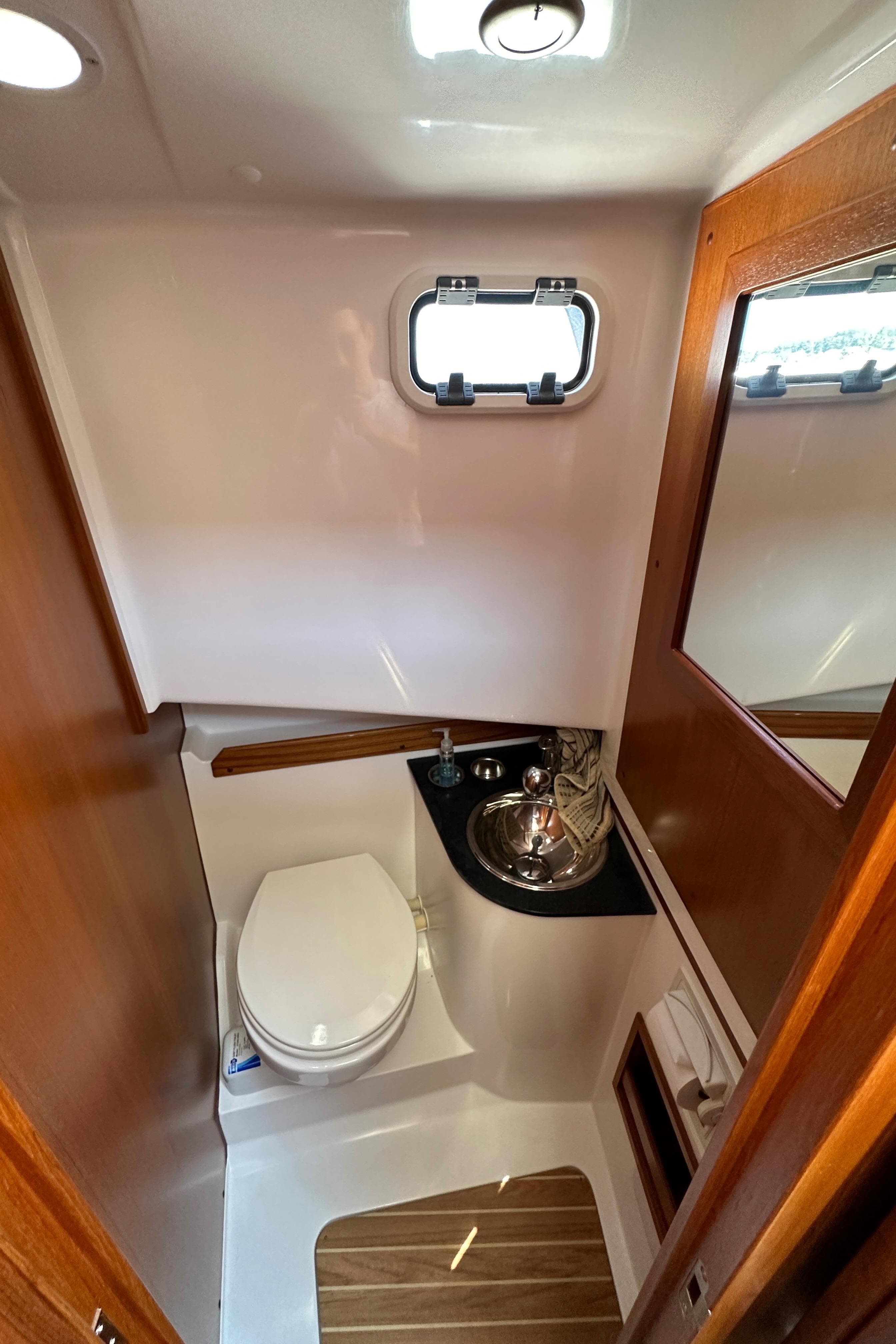Compact bathroom in 2020 Sargo 31 boat with toilet, sink, and wooden accents.
