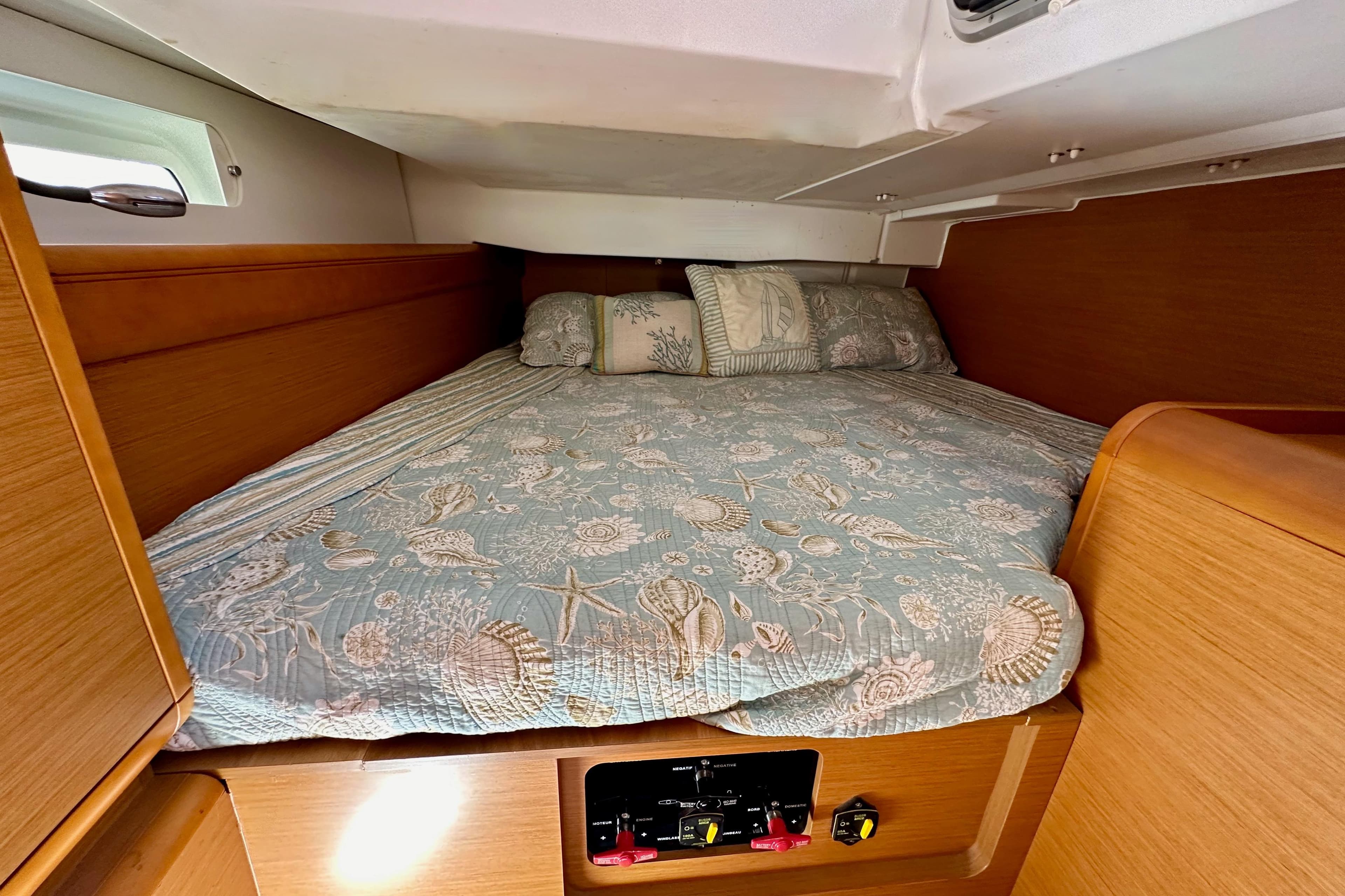 Cozy cabin interior of 2015 Jeanneau Sun Odyssey 409 sailboat with patterned bedding.