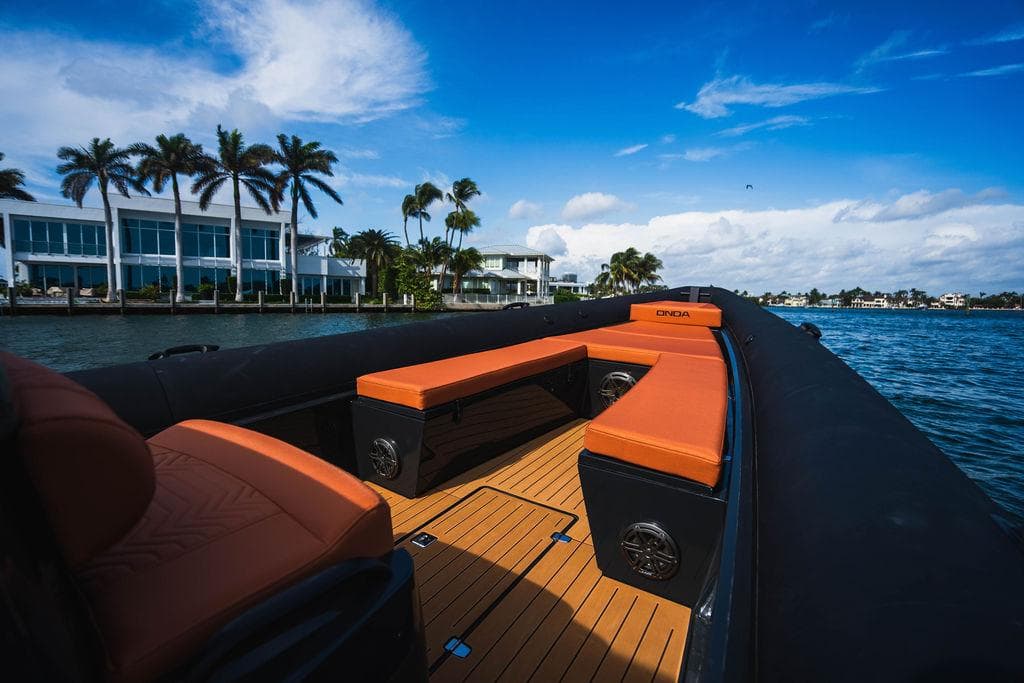 2024 Onda Magna boat with orange seating, cruising near waterfront homes and palm trees.