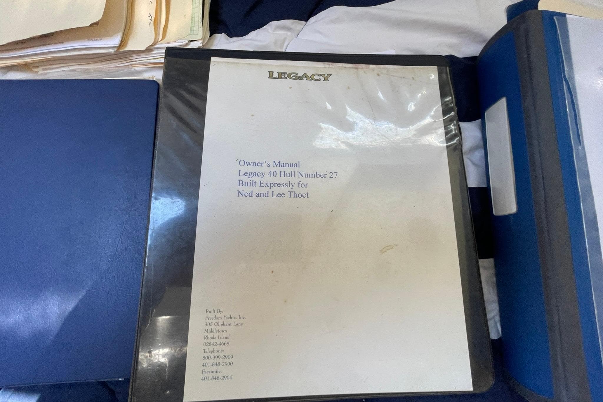 Owner's manual for 1999 Legacy Yachts 40 Sedan, Hull Number 27, on a table.