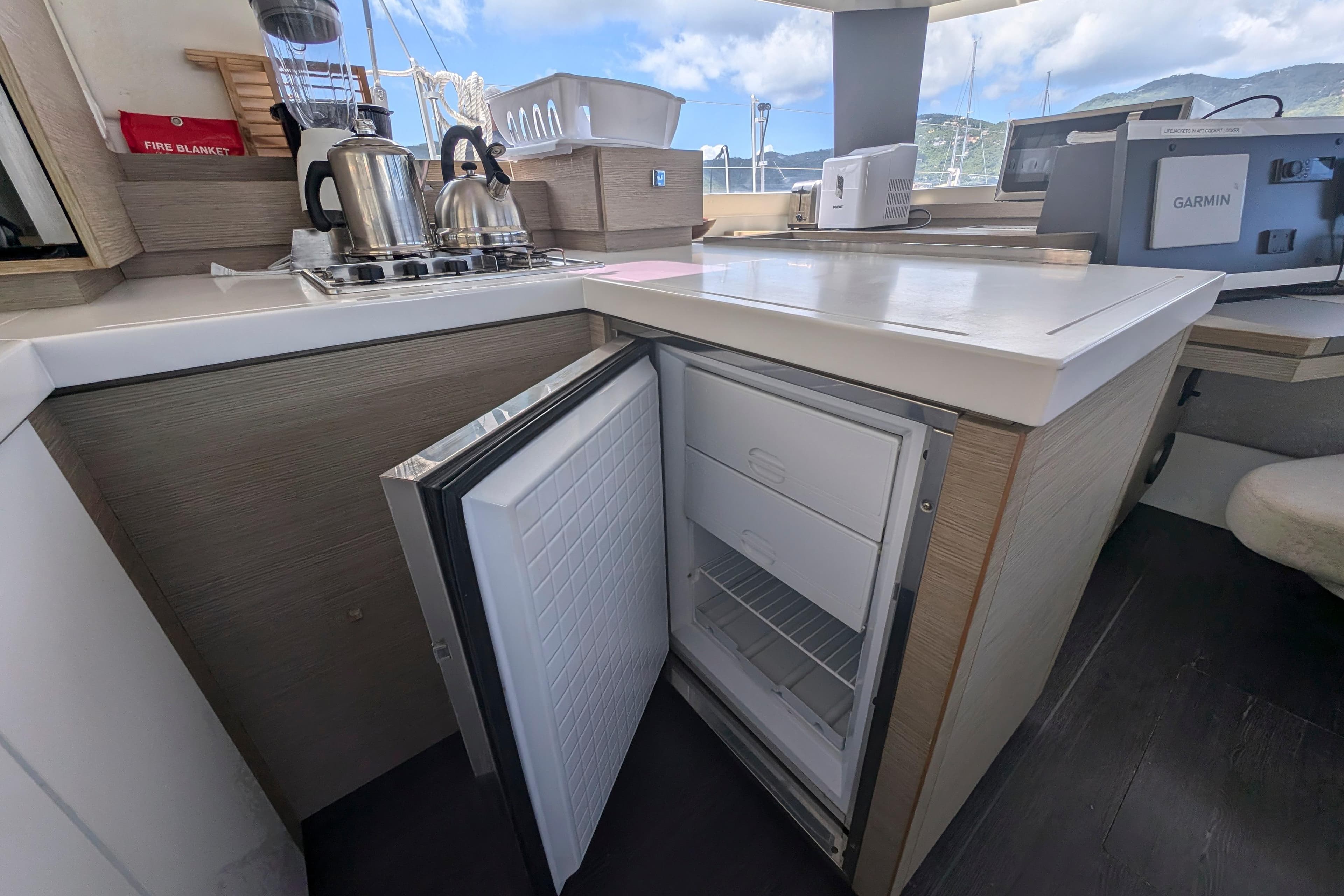 Modern kitchen in 2020 Fountaine Pajot Astrea 42 yacht with open fridge and appliances.