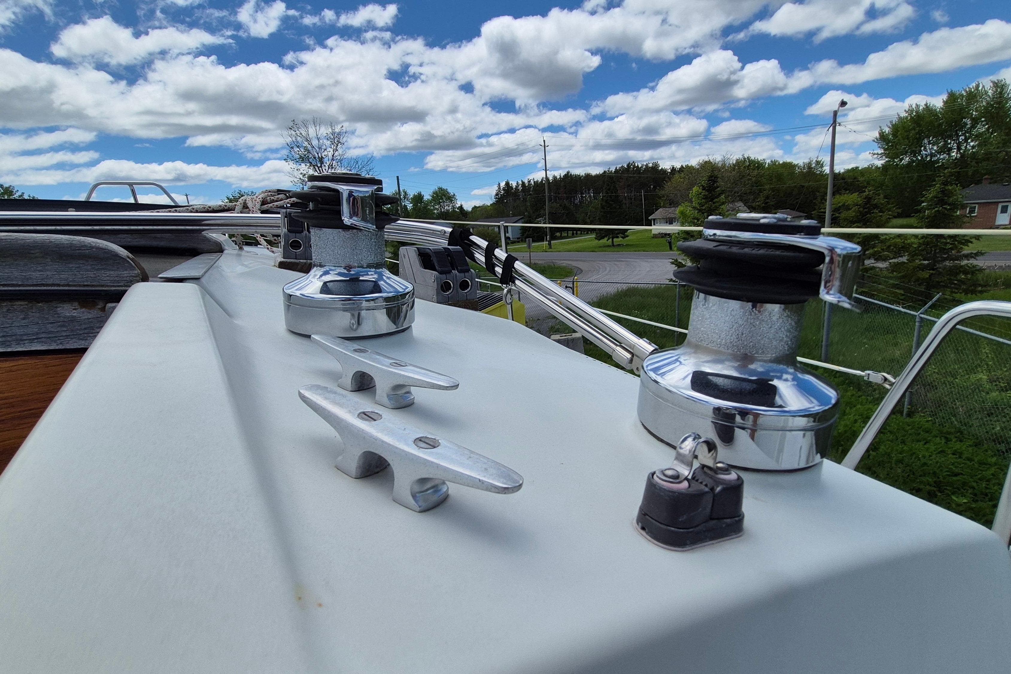 Deck view of a 1991 Ericson 38 sailboat with winches and cleats under a cloudy sky.