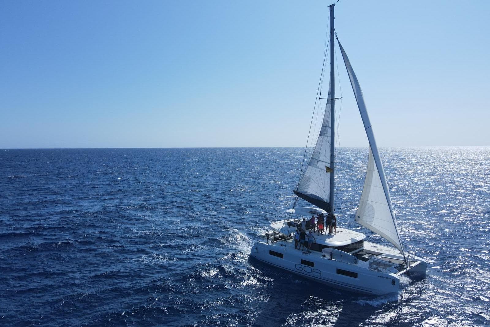 2024 Lagoon 46 sailing catamaran on open sea under clear blue sky.