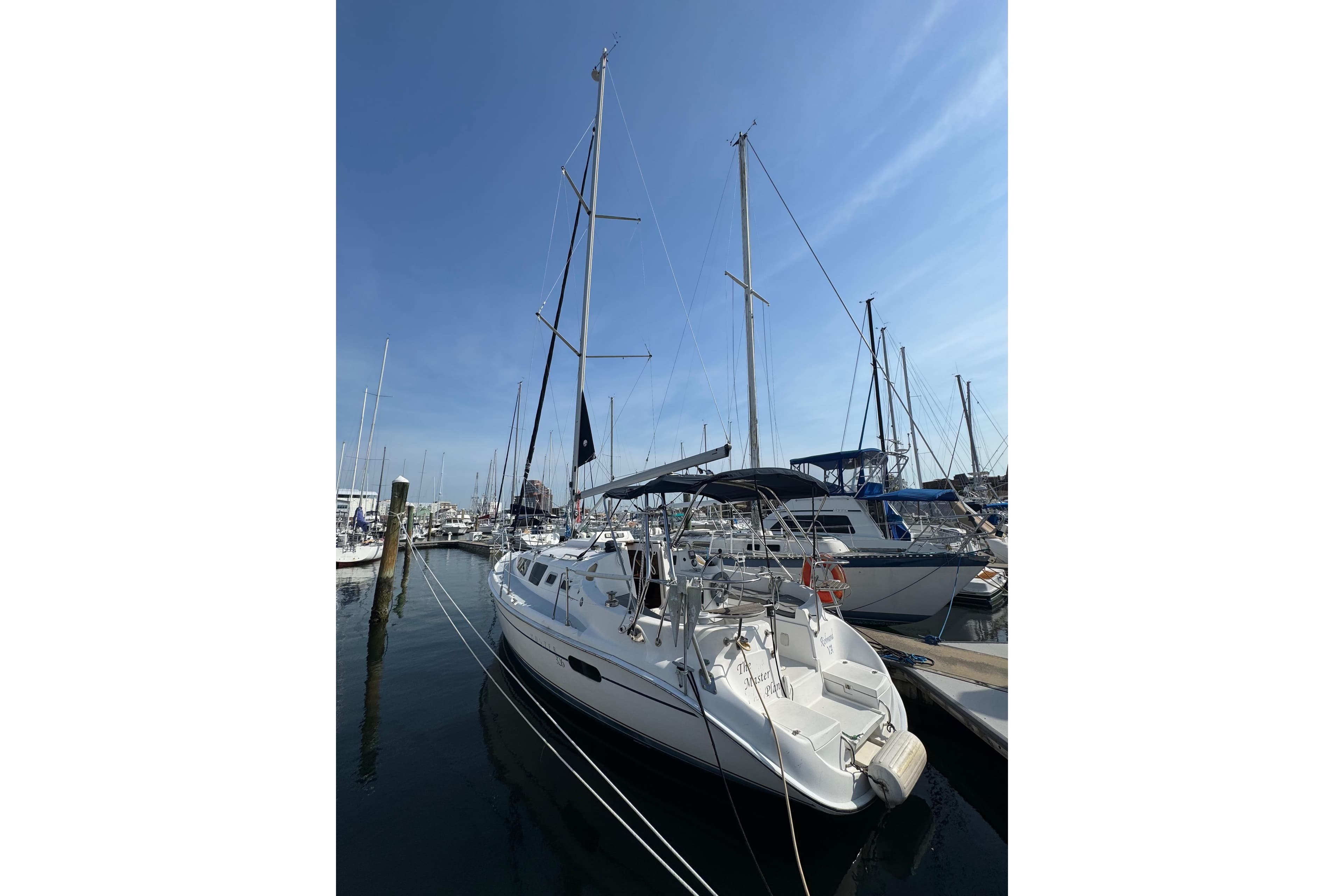 Sailboat Hunter 326, 2002 model, docked at marina under clear blue sky.