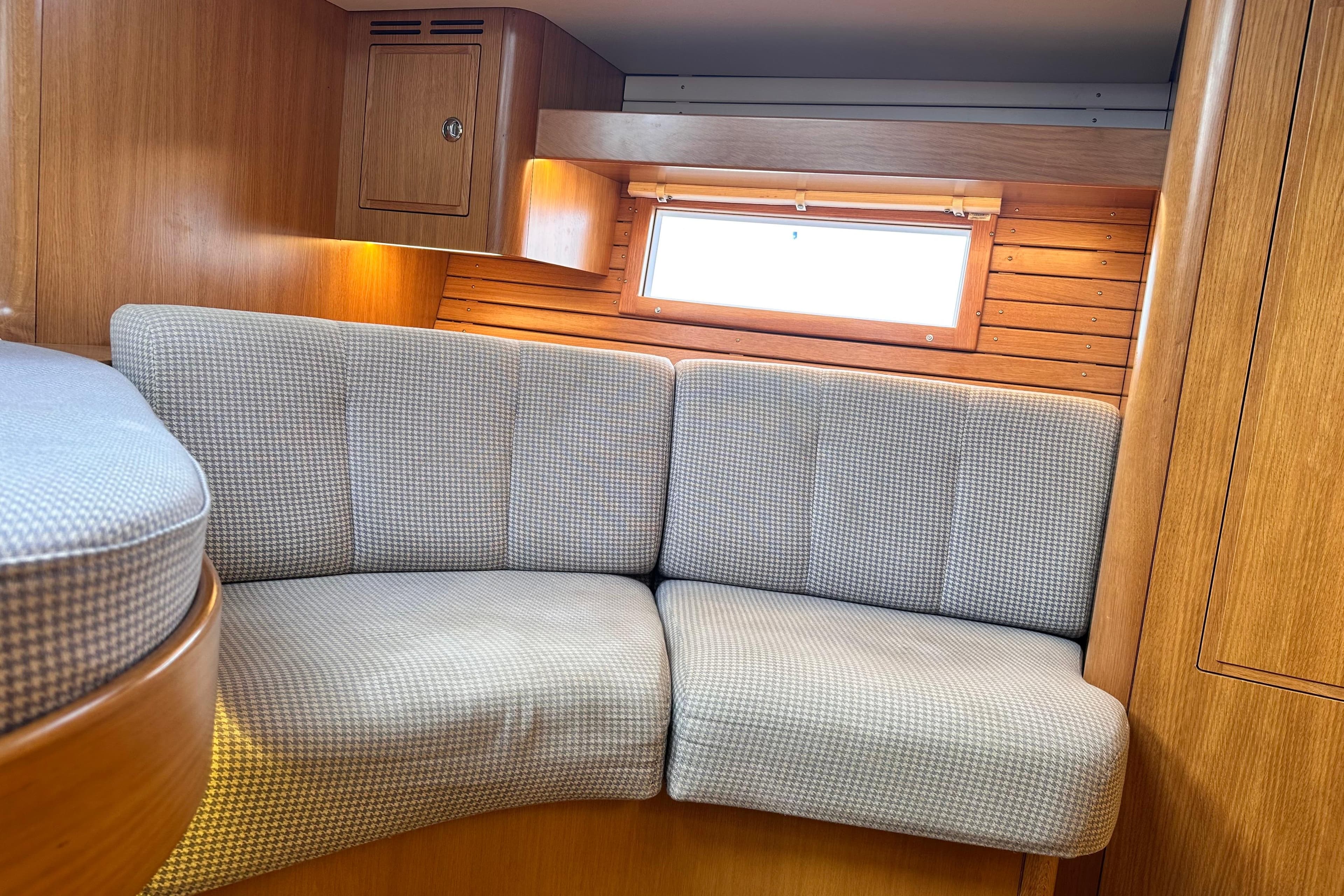 Interior of 2019 Hallberg-Rassy 44 yacht with cozy seating and wooden paneling.