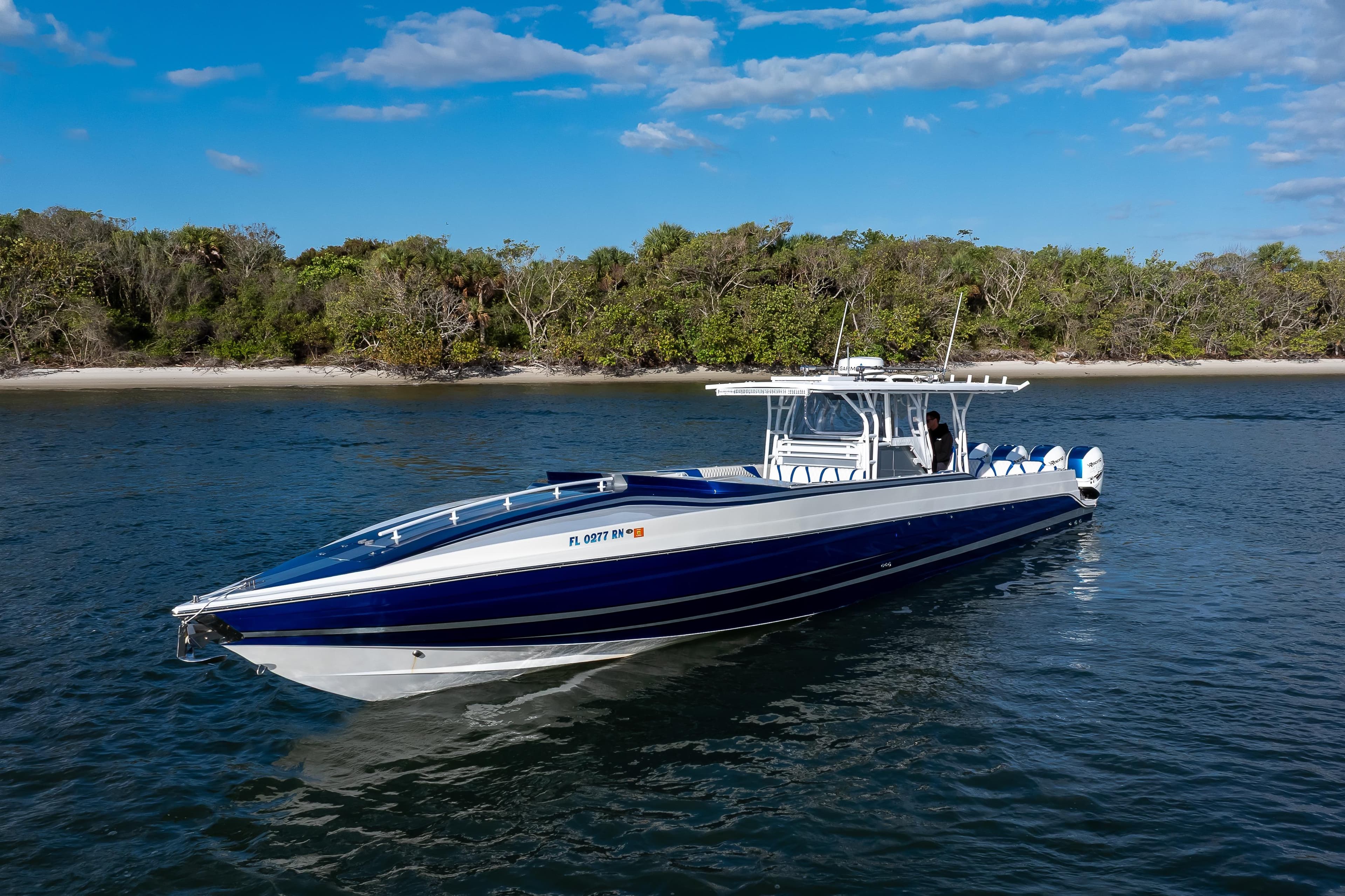2018 Hann 53 boat on water near a forested shoreline under a blue sky.