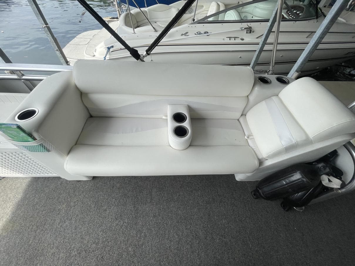 White seating on 1988 Sun Tracker PARTY BARGE with cup holders, docked by water.