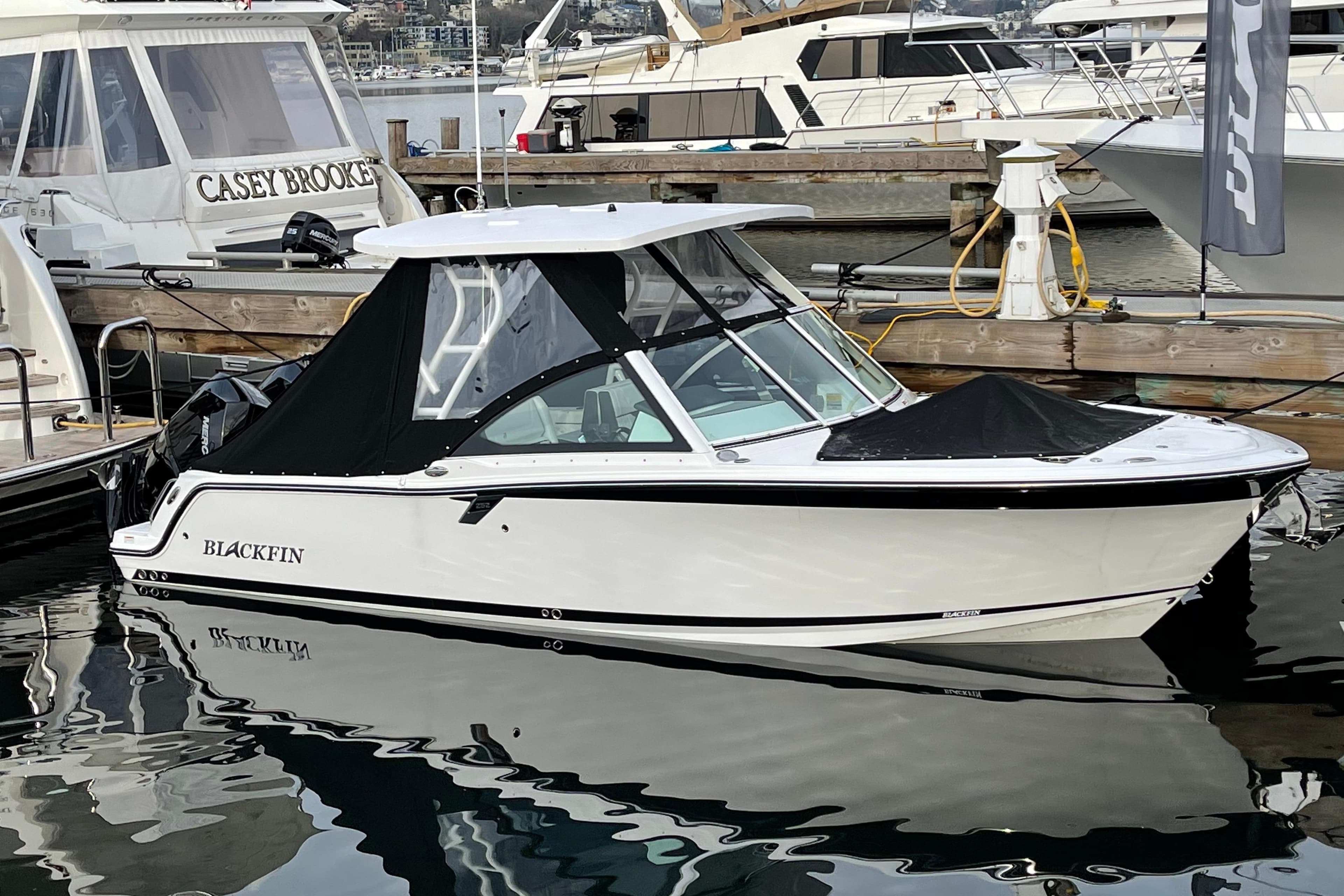 2021 Blackfin 252DC boat docked at marina, featuring sleek design and black canopy.