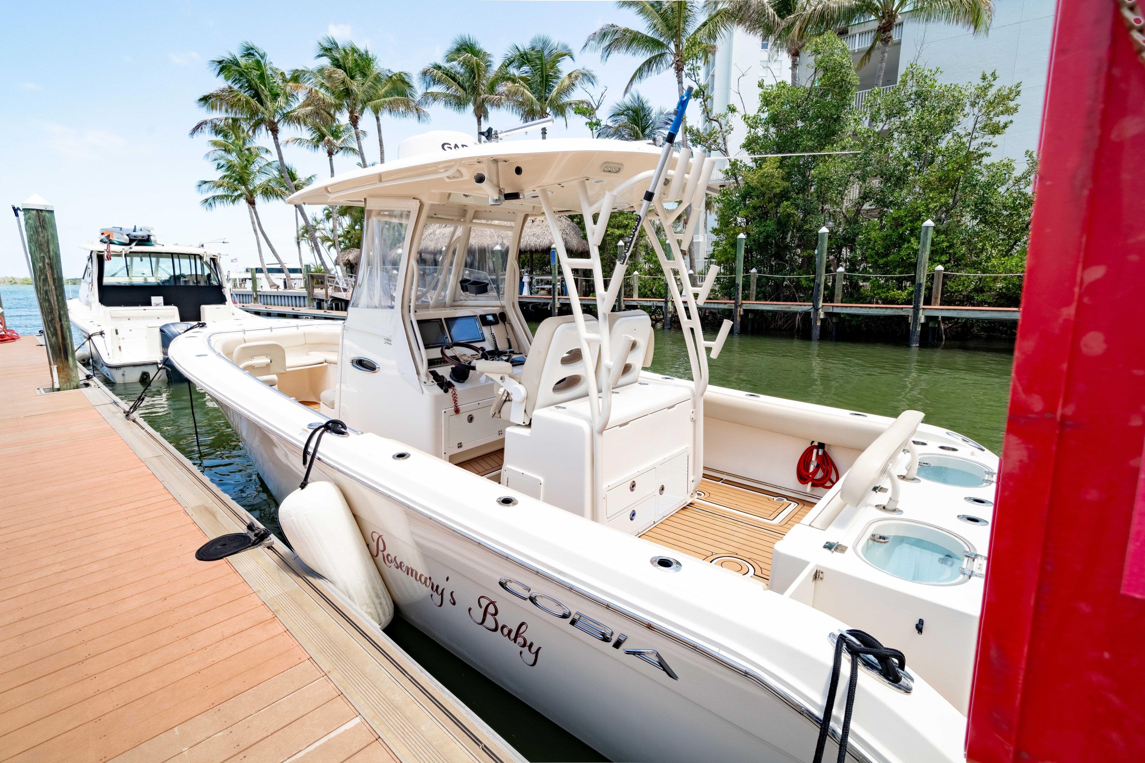 2016 Cobia 296 Center Console boat docked by palm trees.