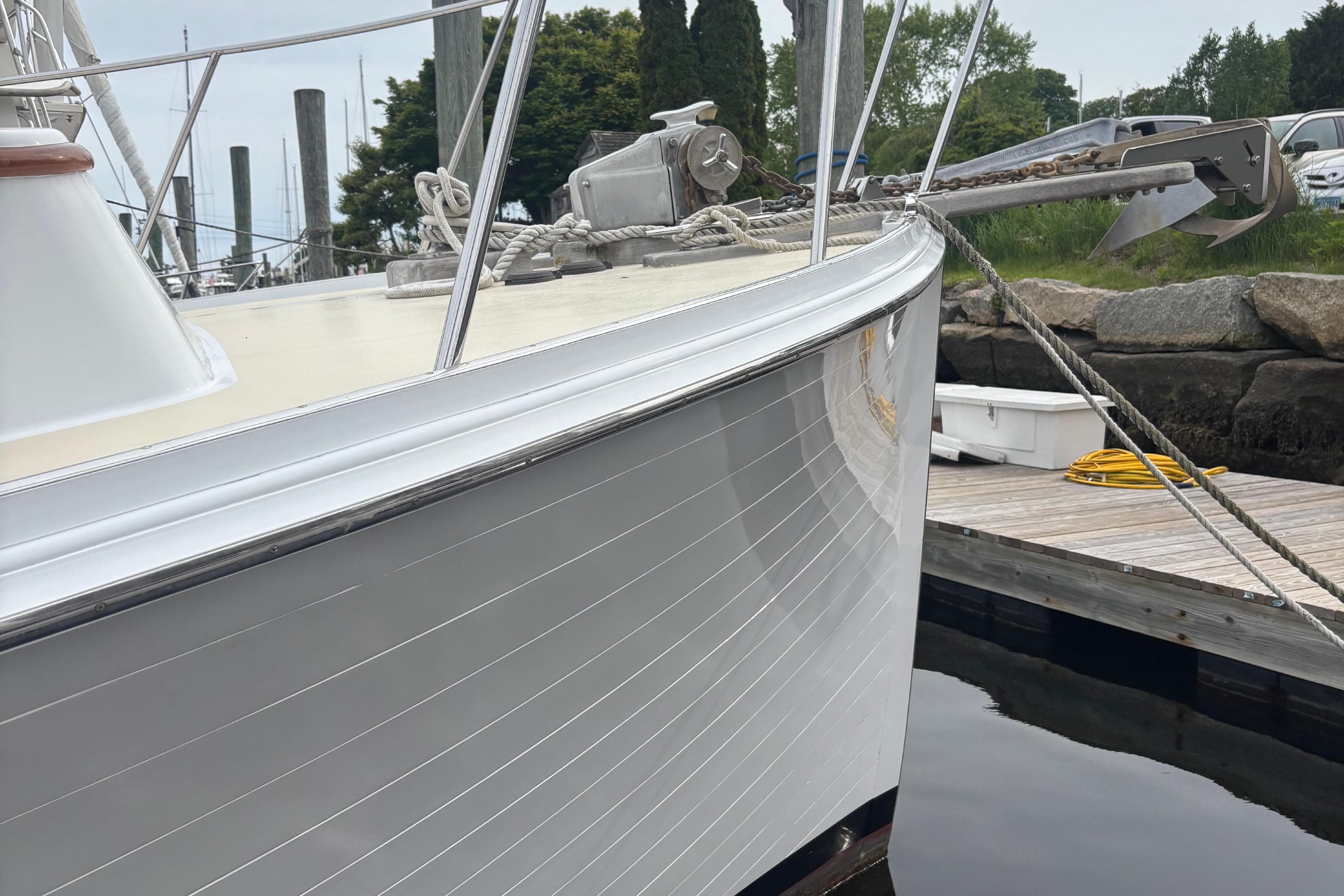 Bow of a 2001 Lowell 40 boat docked, featuring sleek white hull and anchor.