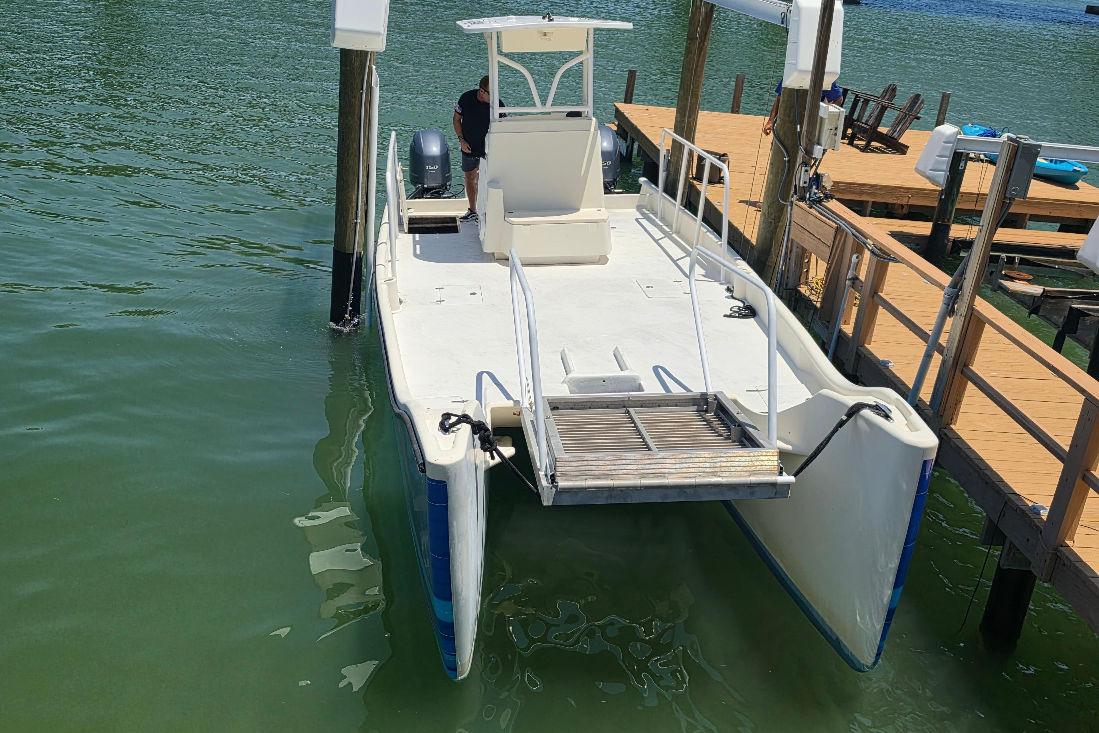 2014 Custom Exuma Catamaran 32 docked on calm water near wooden pier.