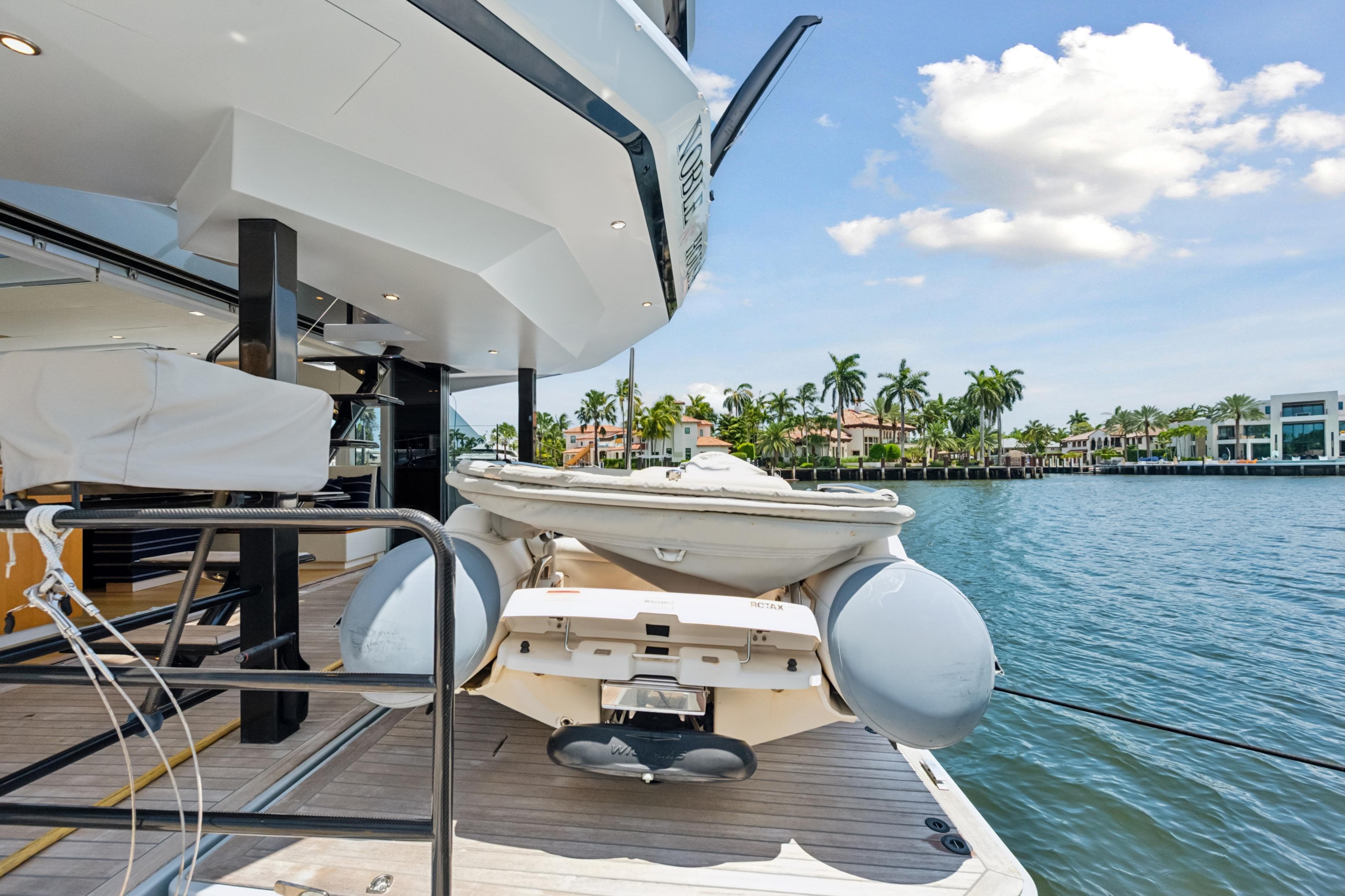 2019 McConaghy MC60 yacht with tender, docked by waterfront homes under a sunny sky.