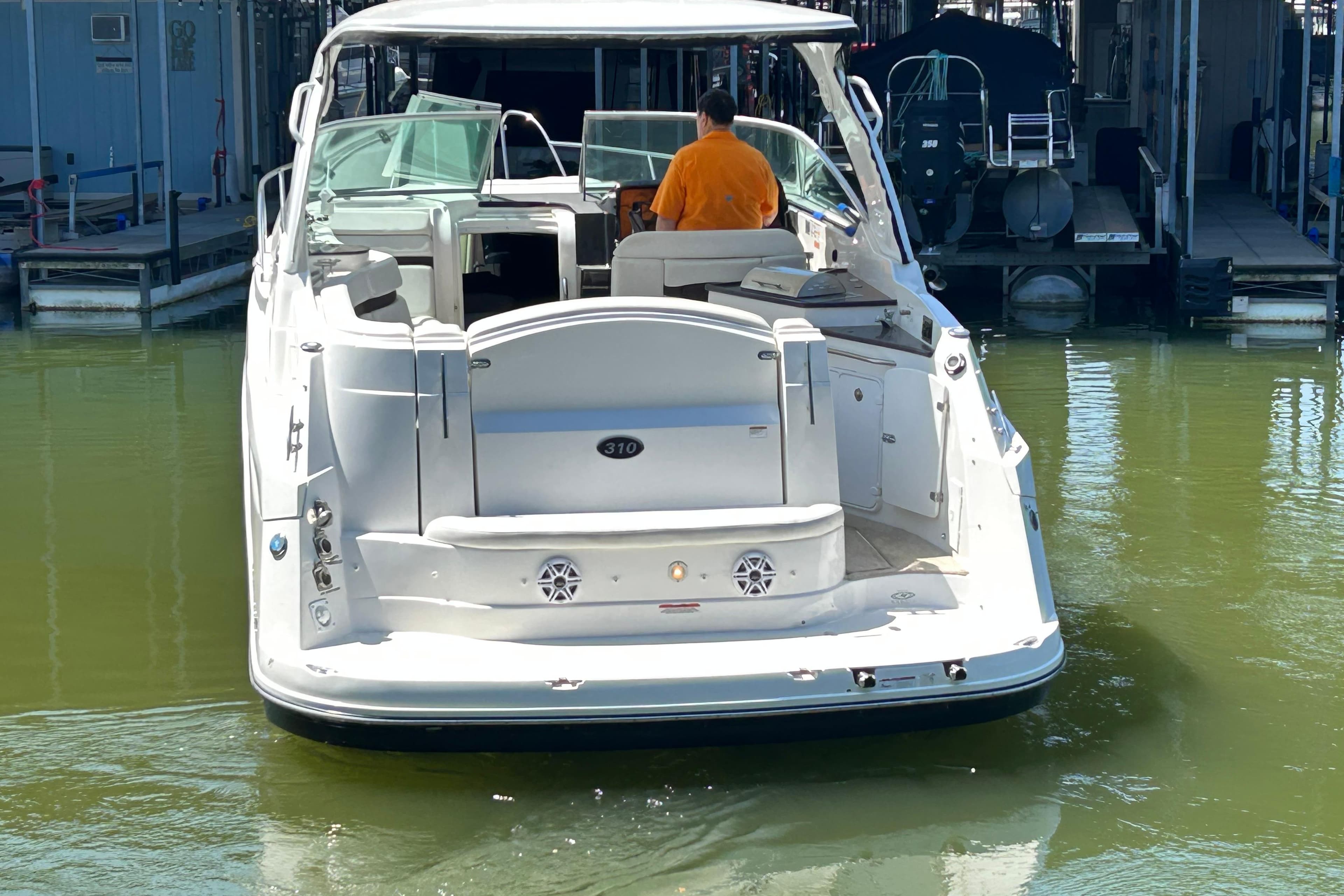 2013 Rinker 310 Express Cruiser docked in marina, rear view.