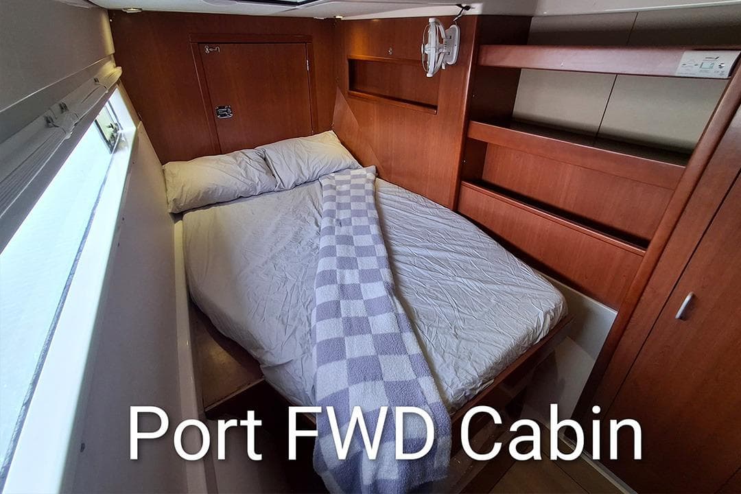 Port forward cabin in 2013 Leopard 48 yacht, featuring cozy bed and wooden interior.