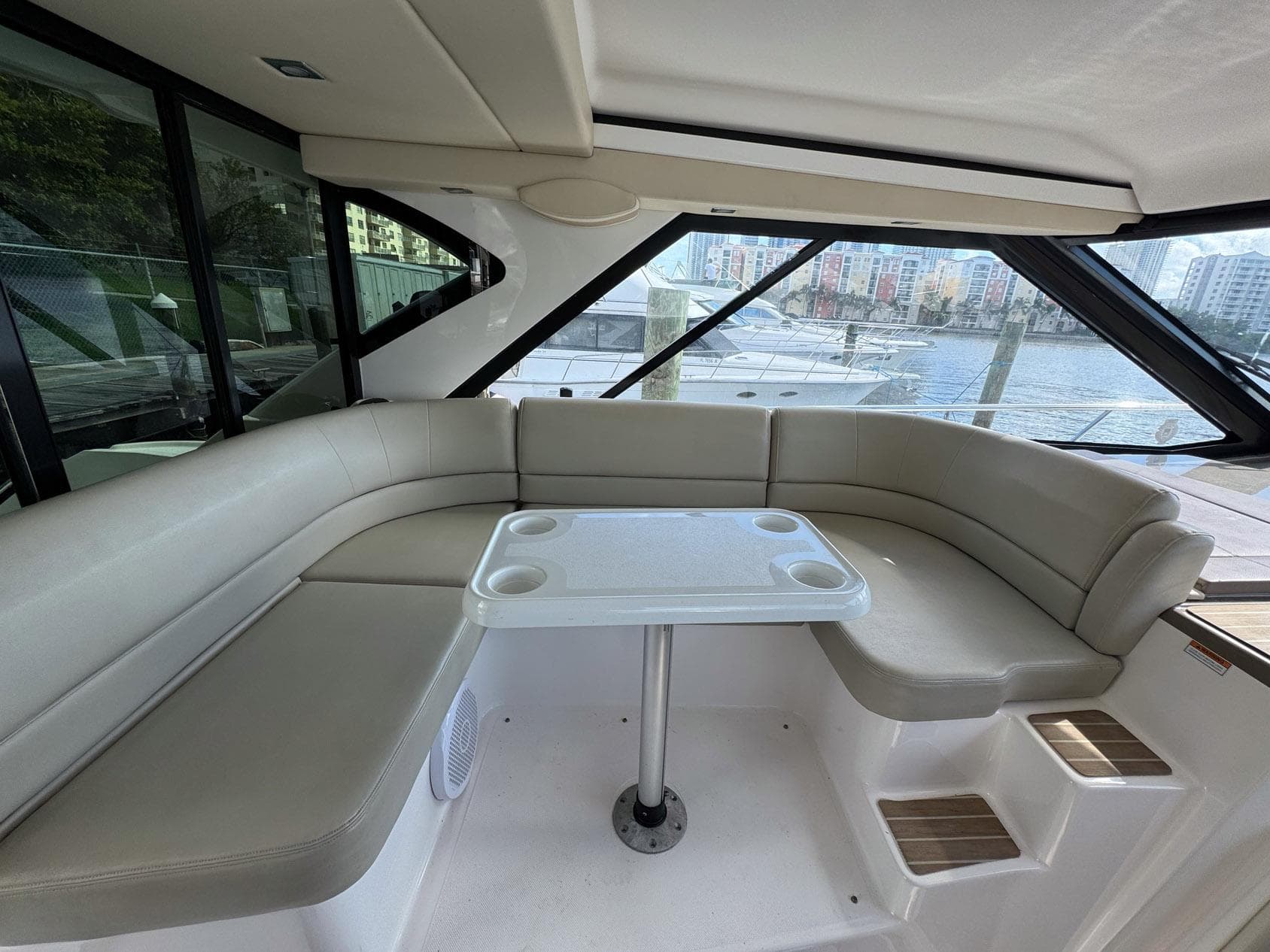 2016 Regal 46 Sport Coupe interior with beige seating and table, overlooking marina.