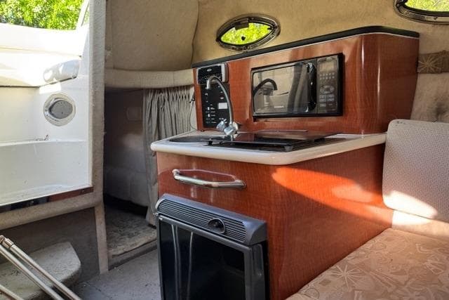 Interior of 2004 Sea Ray 240 Sundancer boat with kitchenette and seating area.