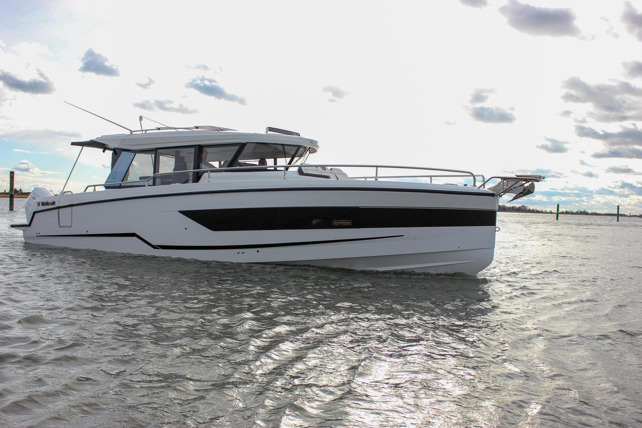 2026 Wellcraft 38 Explorer boat on calm water under cloudy sky.