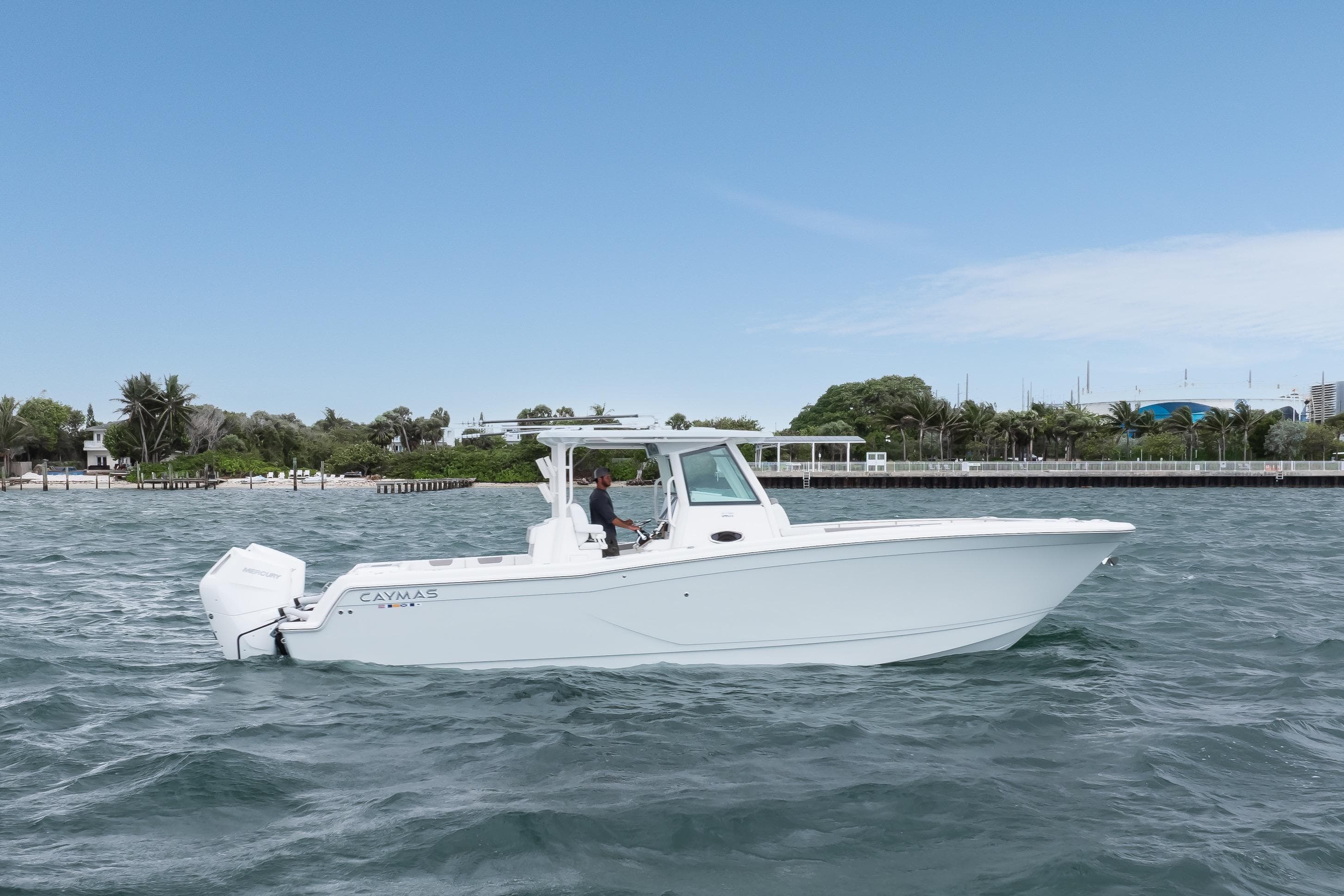 2024 Caymas 341 CC boat cruising on a sunny day near a lush shoreline.