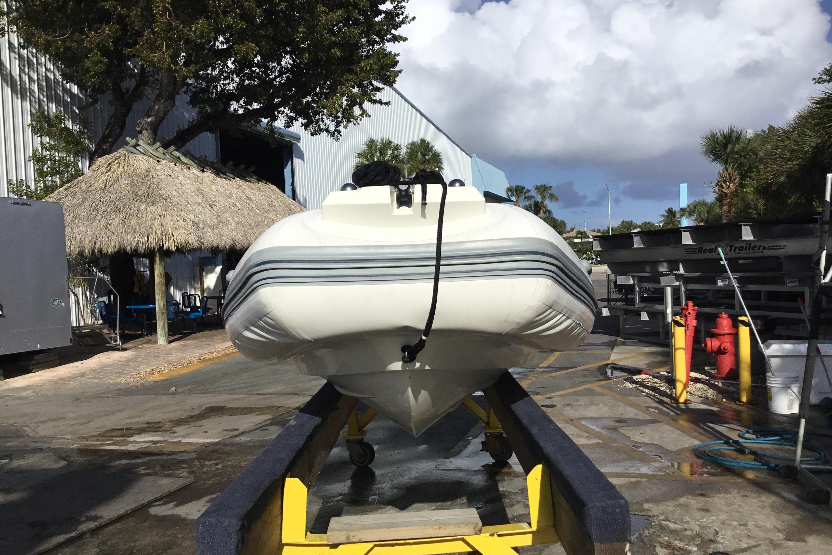 2018 Brig E 480 inflatable boat on trailer, outdoor setting with palm trees and thatched roof.