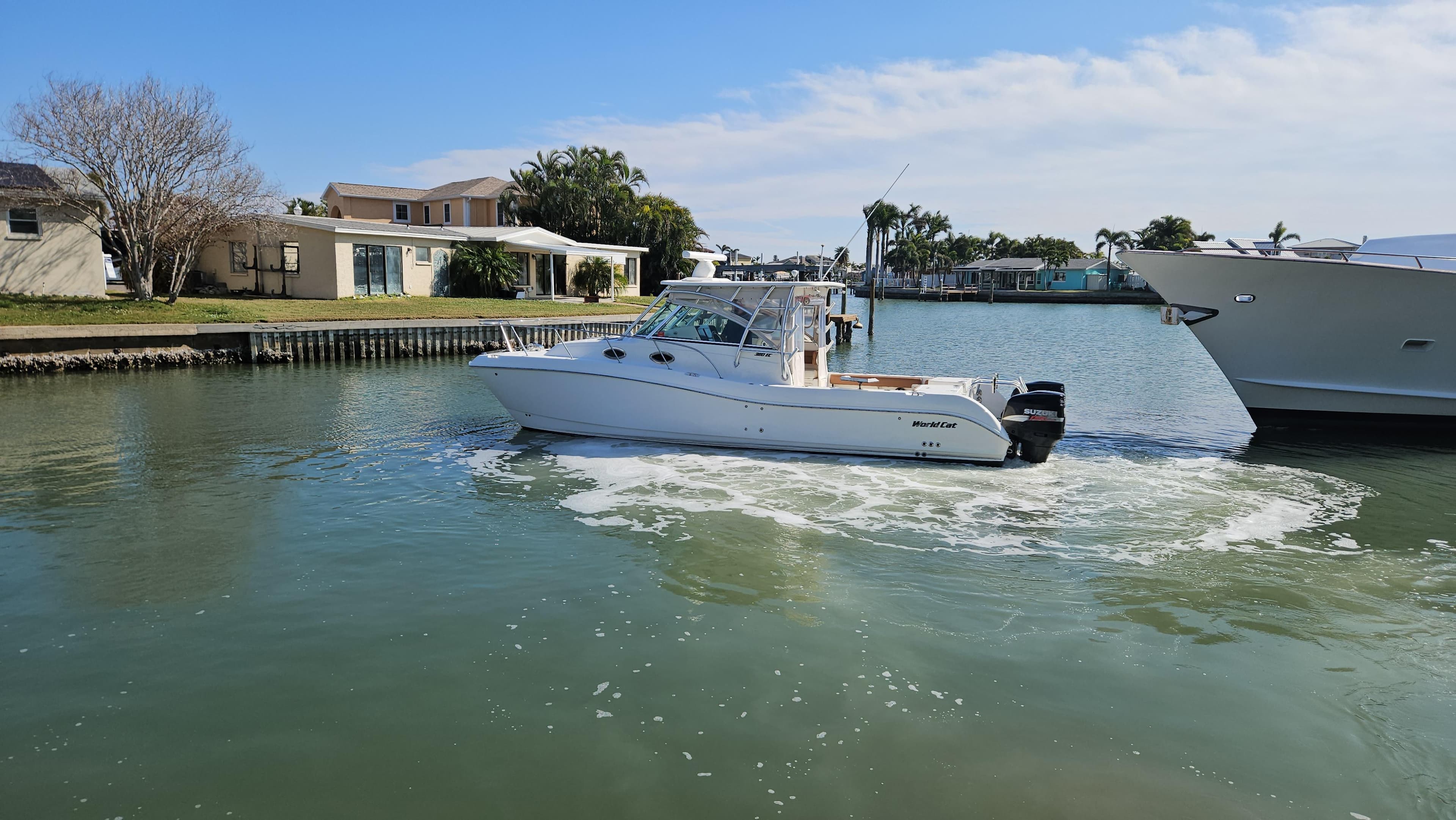2008 World Cat 320 EC boat cruising in a calm residential canal.
