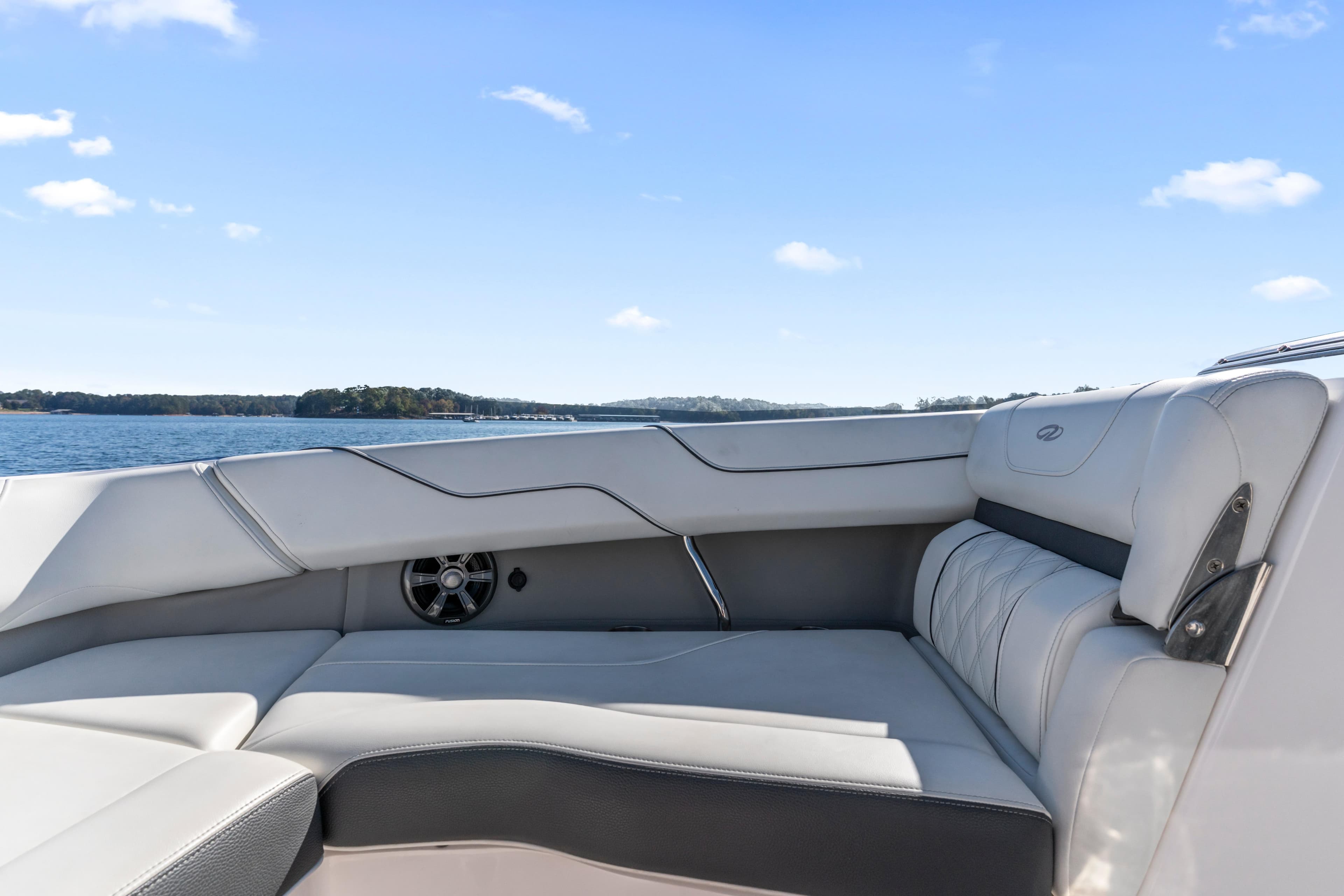 2021 Regal LS6 boat interior with luxurious seating, overlooking serene water and clear blue sky.