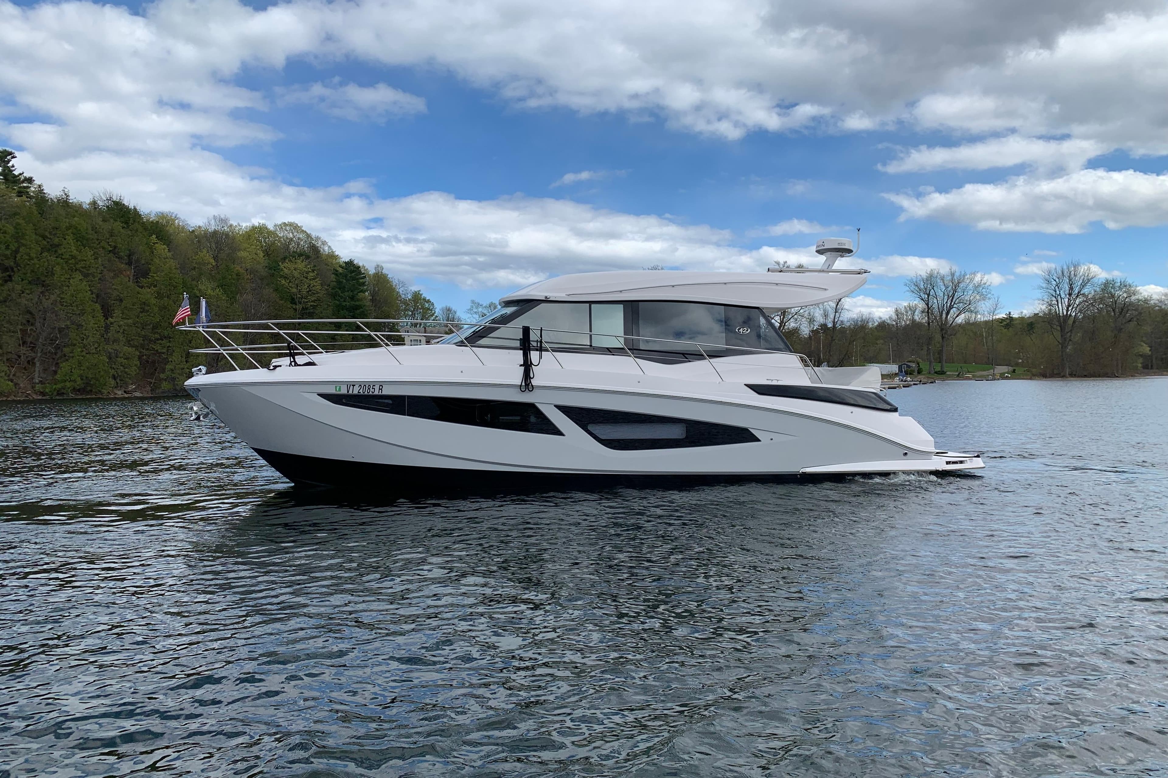 2019 Regal 42 Grande Coupe yacht cruising on a serene lake under a partly cloudy sky.