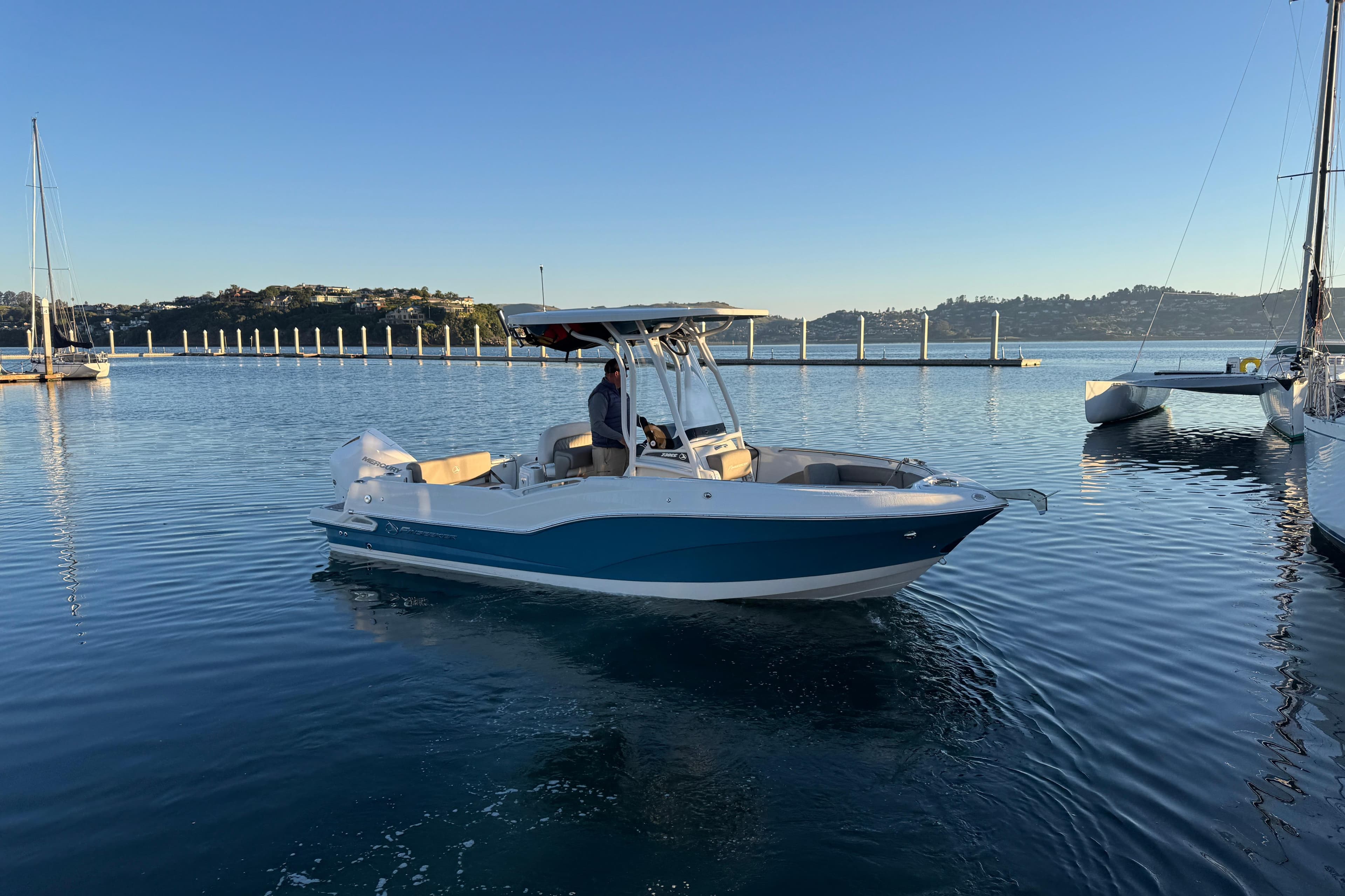 2023 Finseeker 230 CC boat on calm water near a marina.