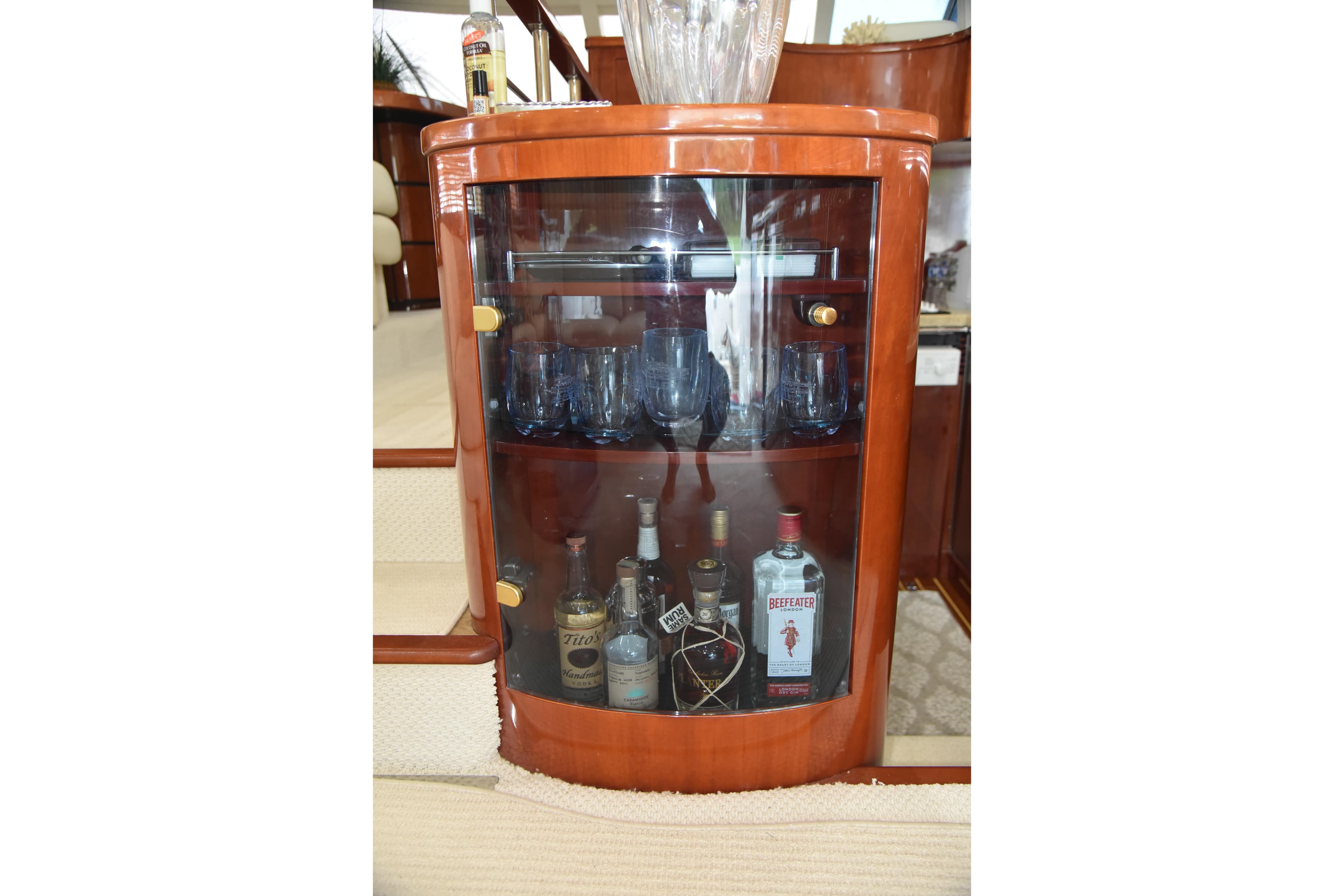 Luxurious wooden liquor cabinet on 2002 Fairline Squadron 58 yacht, featuring glassware and spirits.