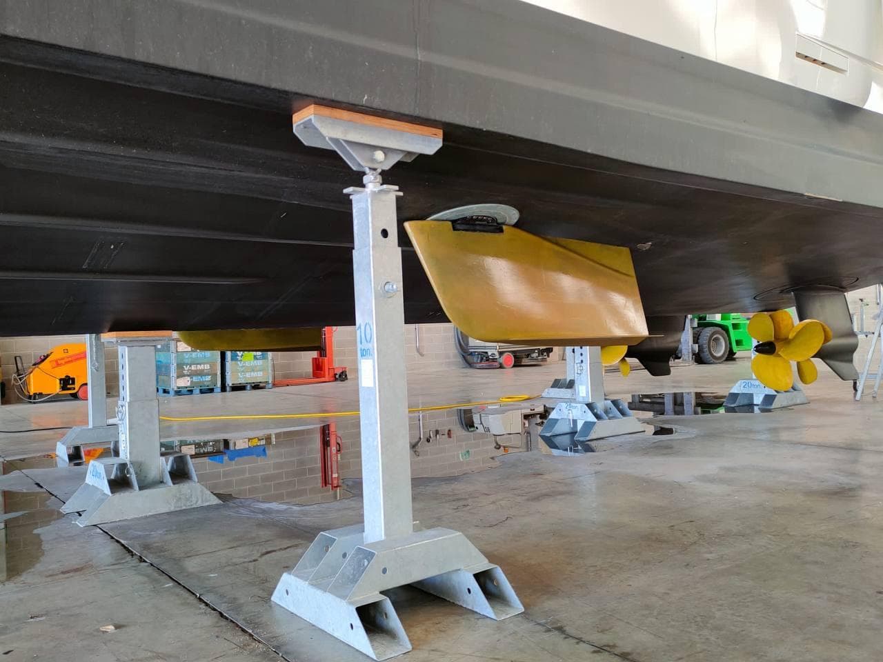 2022 Cranchi Sessantasette 67 yacht hull in maintenance, supported by stands in a workshop.