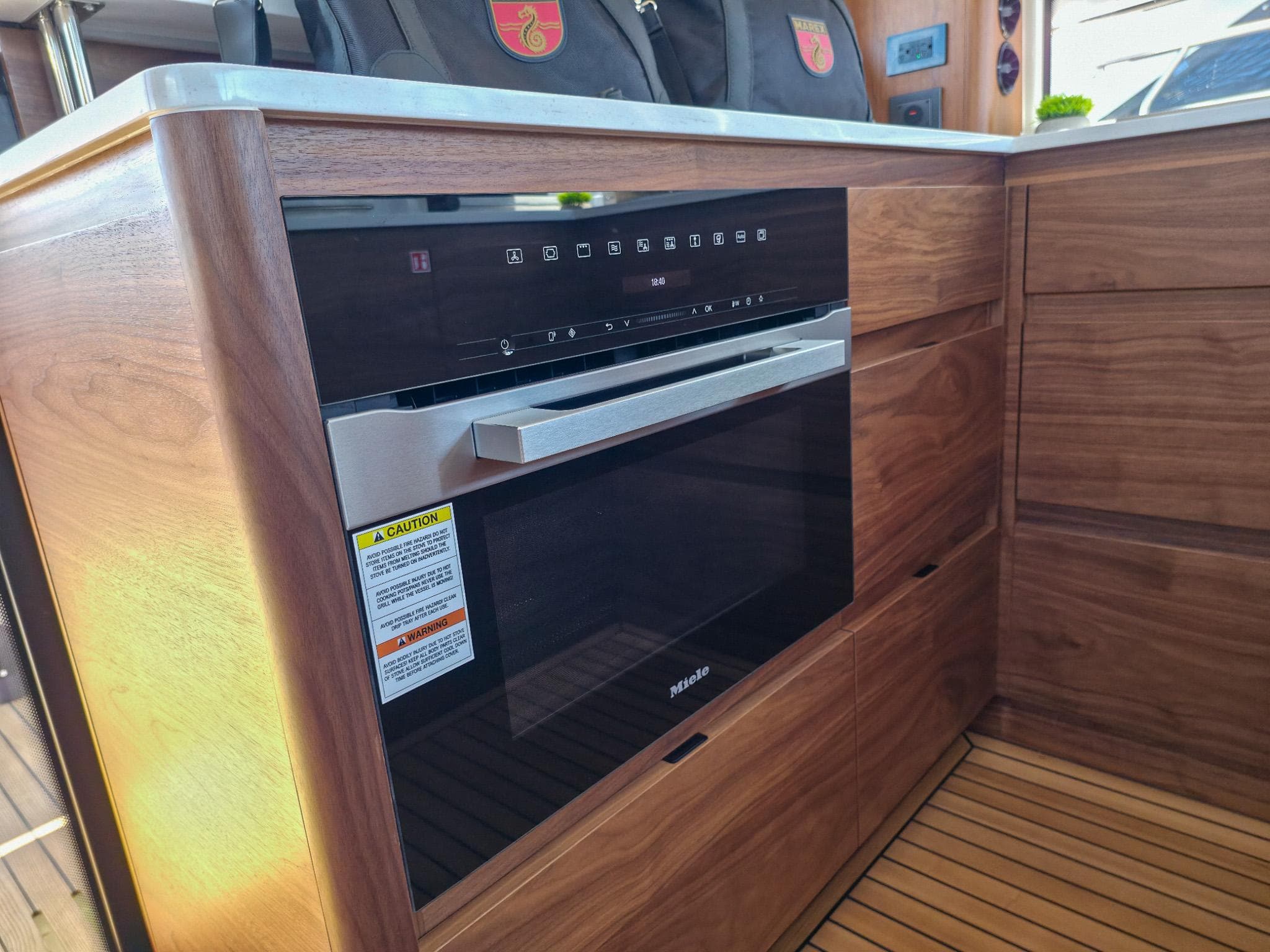 Modern kitchen with Miele oven in 2026 Marex 440 yacht, featuring sleek wood cabinetry.