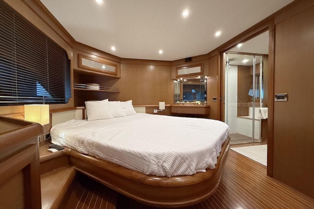Luxurious bedroom interior of 2008 Mochi Craft 64' Dolphin yacht with wood finishes and ensuite bathroom.