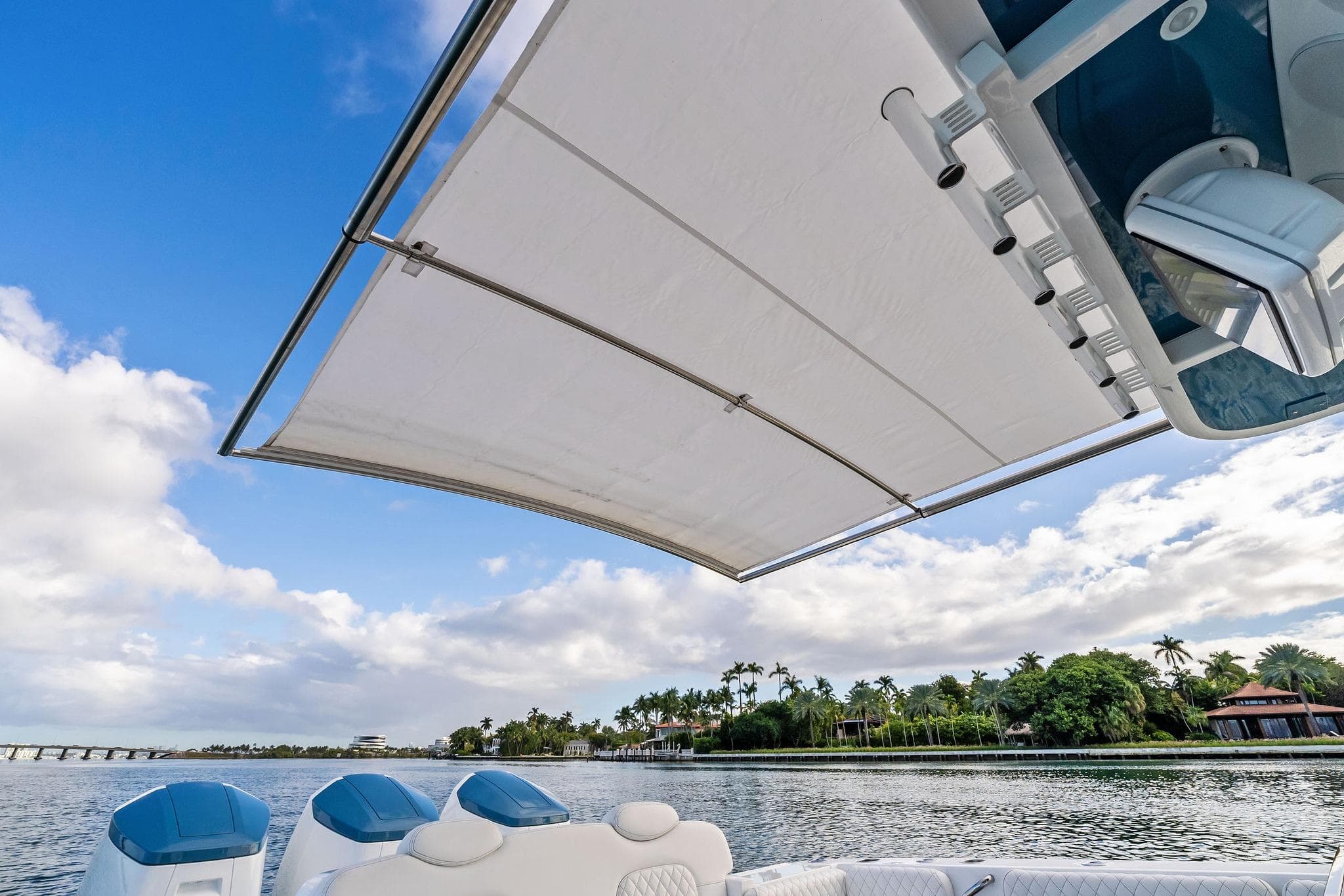 2023 HCB 42 Lujo boat with canopy, scenic waterfront view, blue sky.