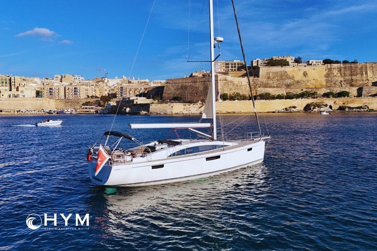 Sailing yacht Bavaria Vision 46, 2014, in scenic harbor with historic buildings.