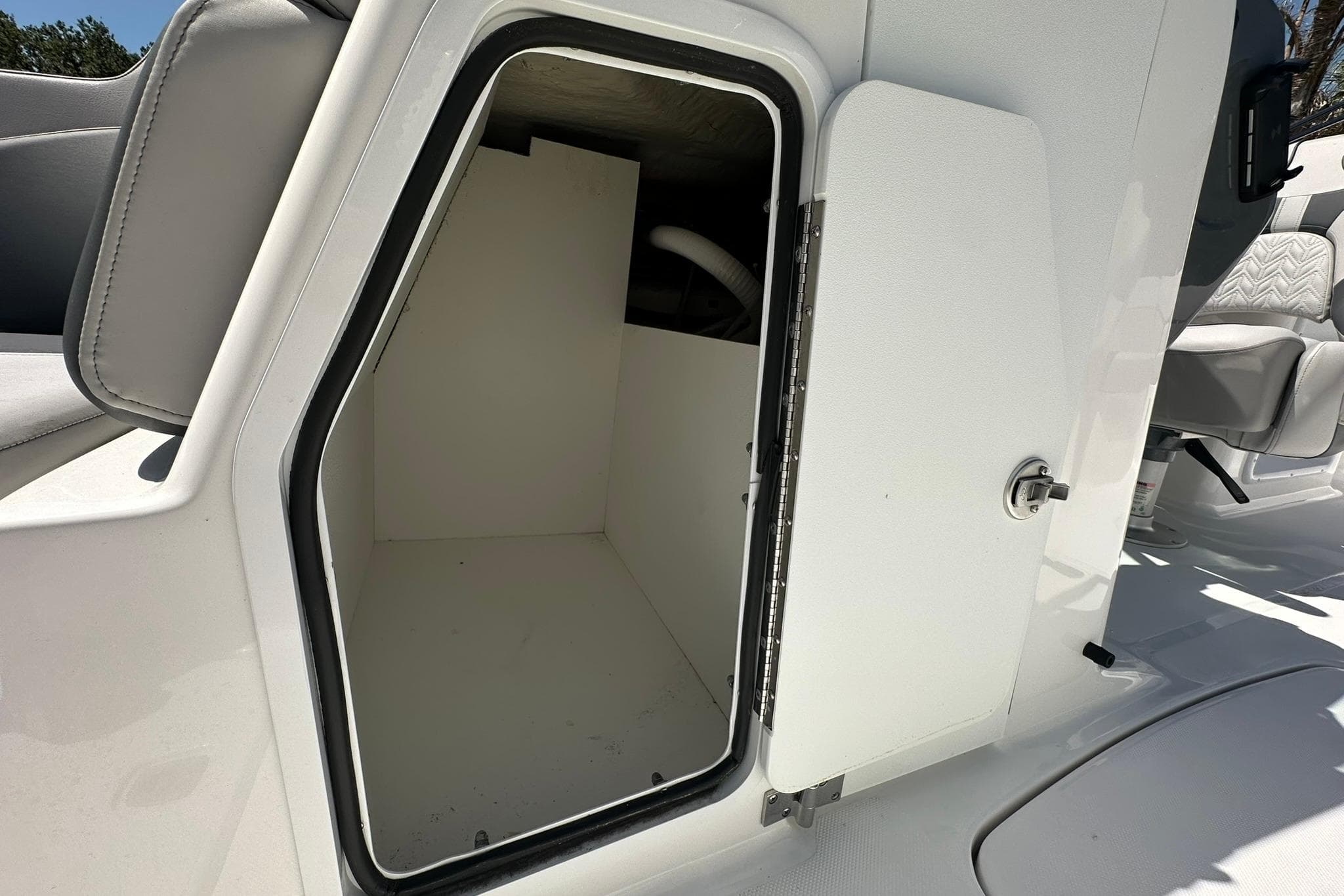 Open storage compartment on 2026 Hurricane SunDeck 2400 OB boat, featuring sleek white interior.