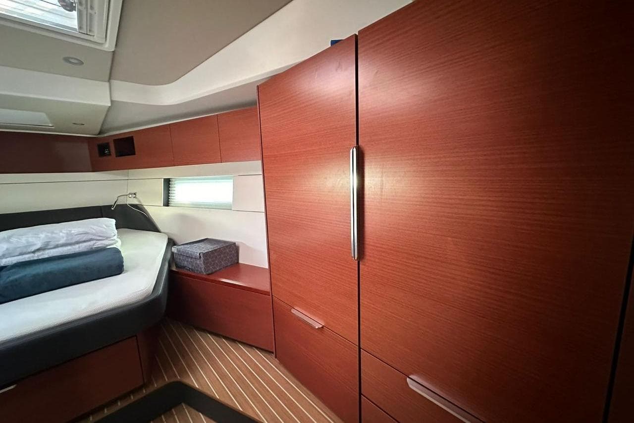 Luxurious interior of 2023 Hanse 460 yacht with wooden cabinetry and cozy bedding.