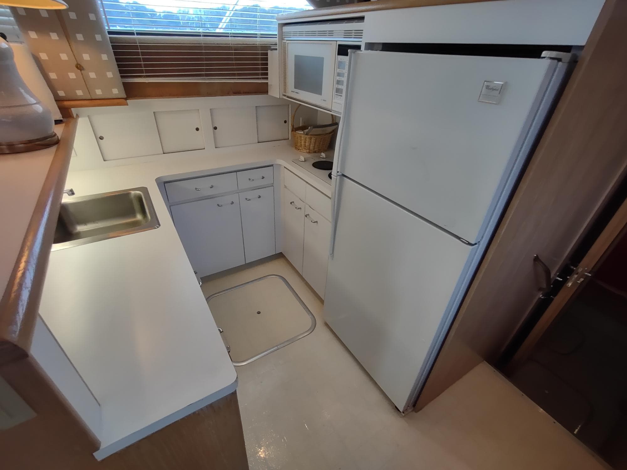 1996 Hatteras 50' Sport Deck kitchen with white cabinetry, fridge, and microwave.