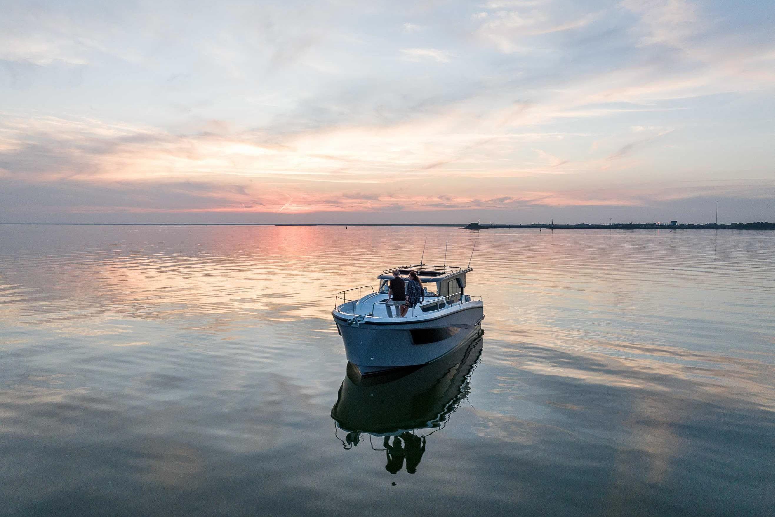 2026 Delphia D10 Sedan cruising on serene waters at sunset.