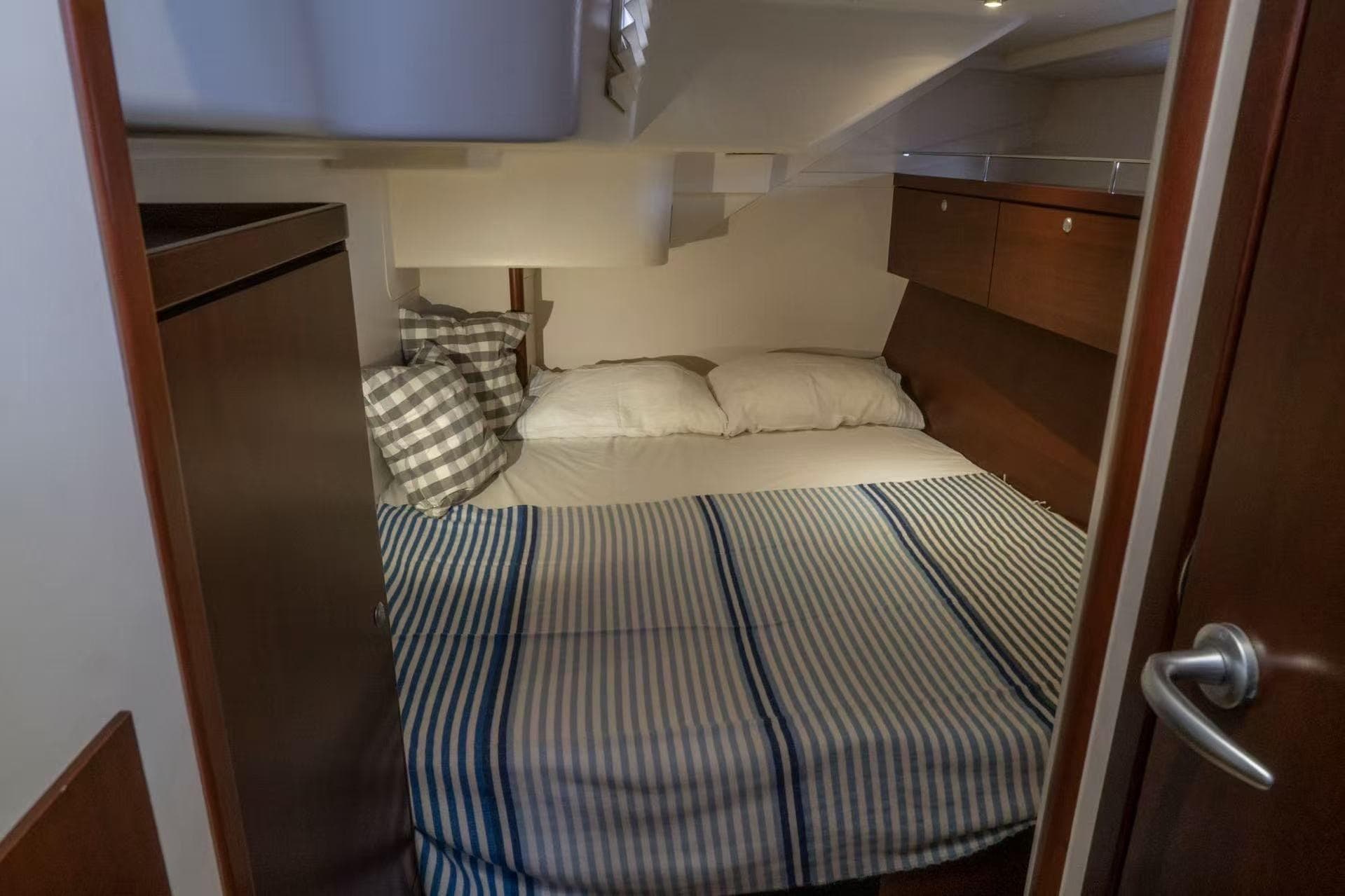 Cozy cabin interior of 2007 Hanse 540e yacht with striped bedding and wooden accents.