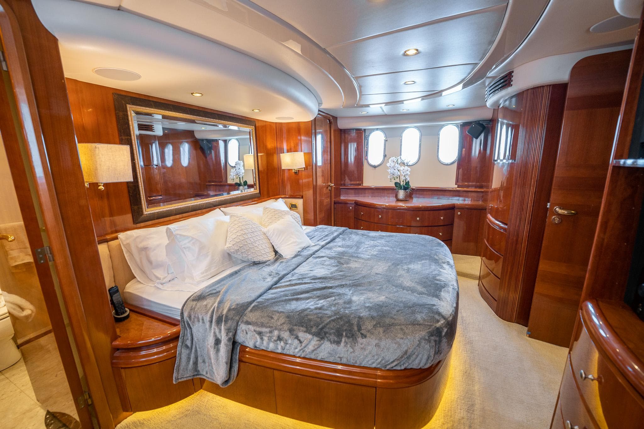 Luxurious master bedroom on a 2004 Azimut 80 Carat yacht with elegant wood finishes.
