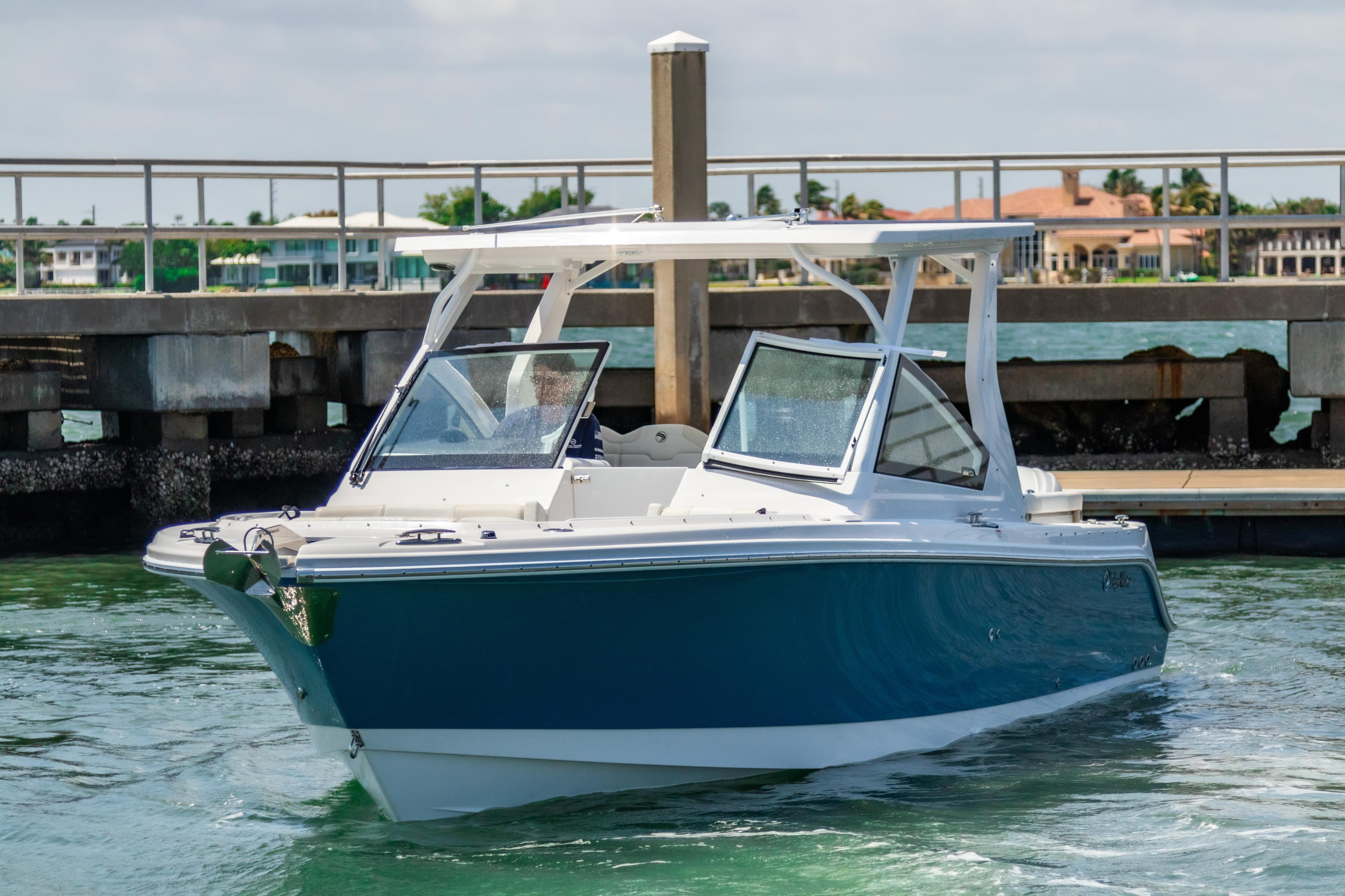 2025 Edgewater 262 CX boat cruising near a dock on a sunny day.